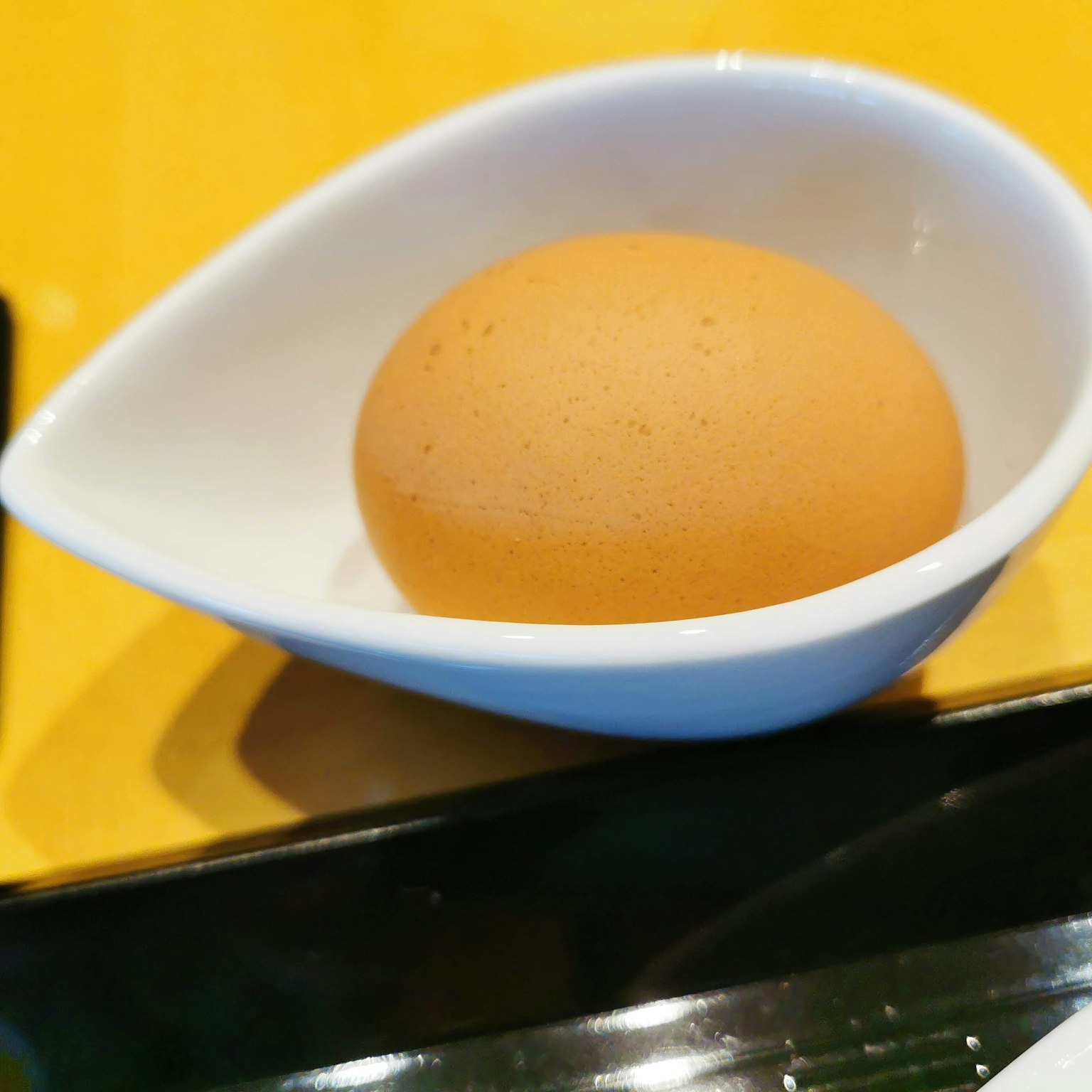 Un œuf orange dans un plat blanc
