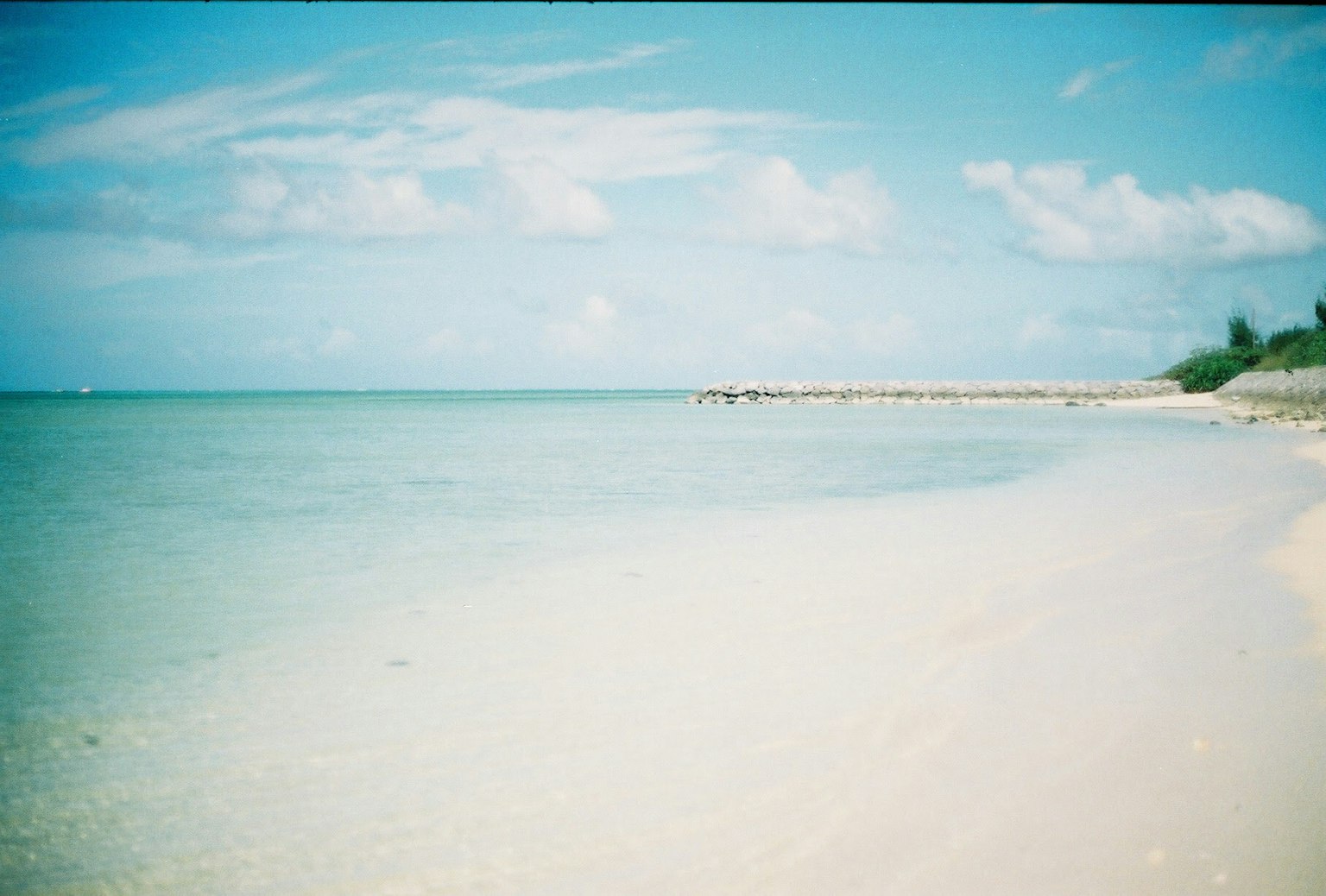 ทิวทัศน์ชายหาดที่เงียบสงบพร้อมน้ำสีฟ้าและทรายขาวใต้ท้องฟ้าที่แจ่มใส