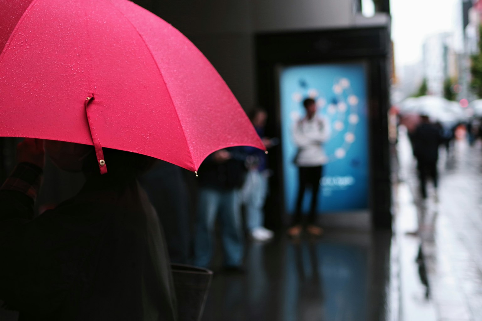 คนถือร่มสีชมพูในฉากเมืองที่มีฝนตก