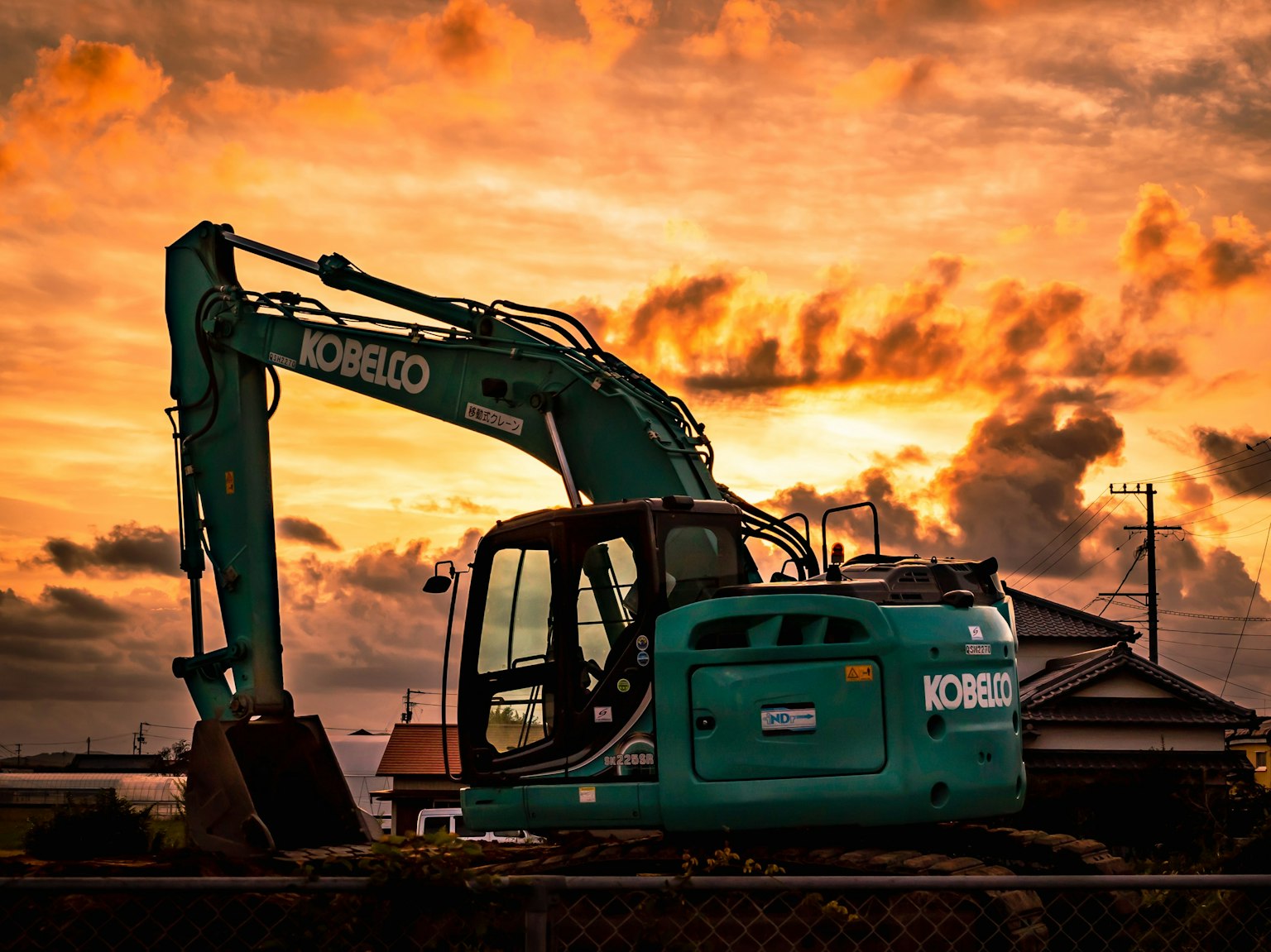 Ekskavator Komatsu bersiluet di latar belakang matahari terbenam yang cerah