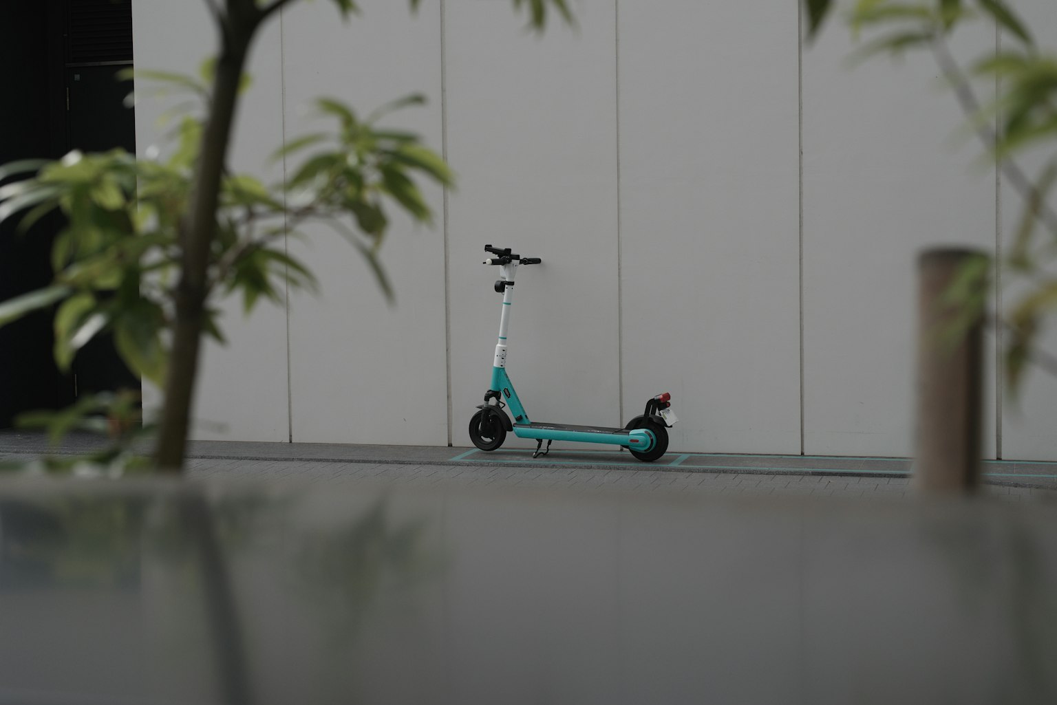 Une trottinette électrique turquoise garée devant un mur