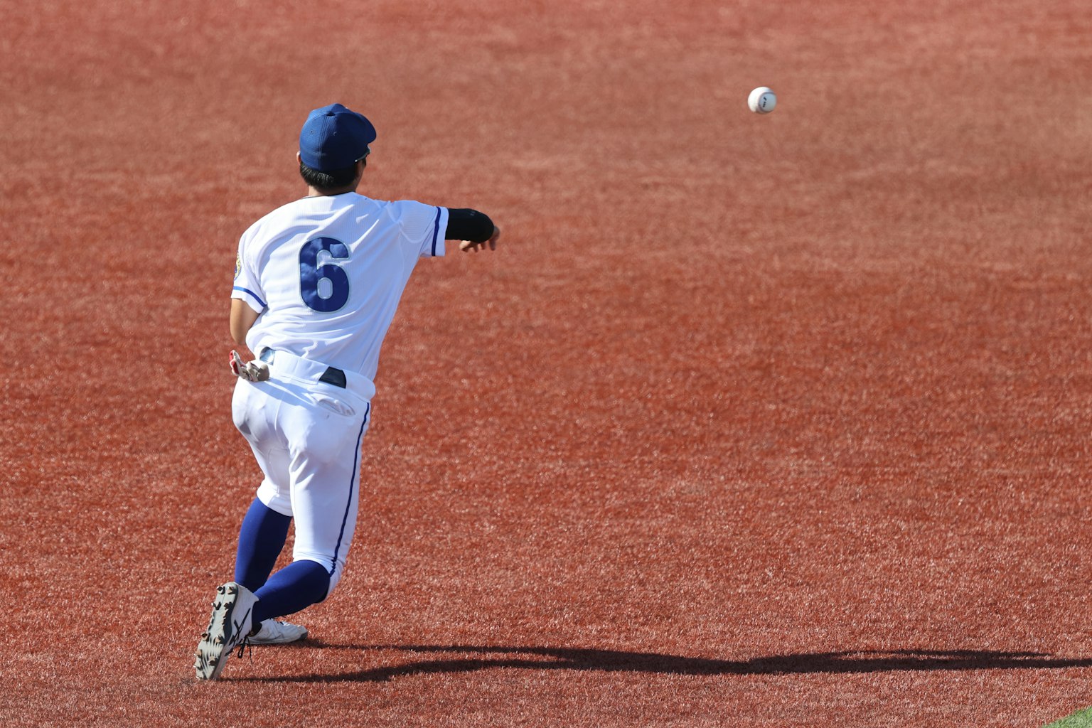 Un giocatore di baseball che lancia una palla su un campo rosso