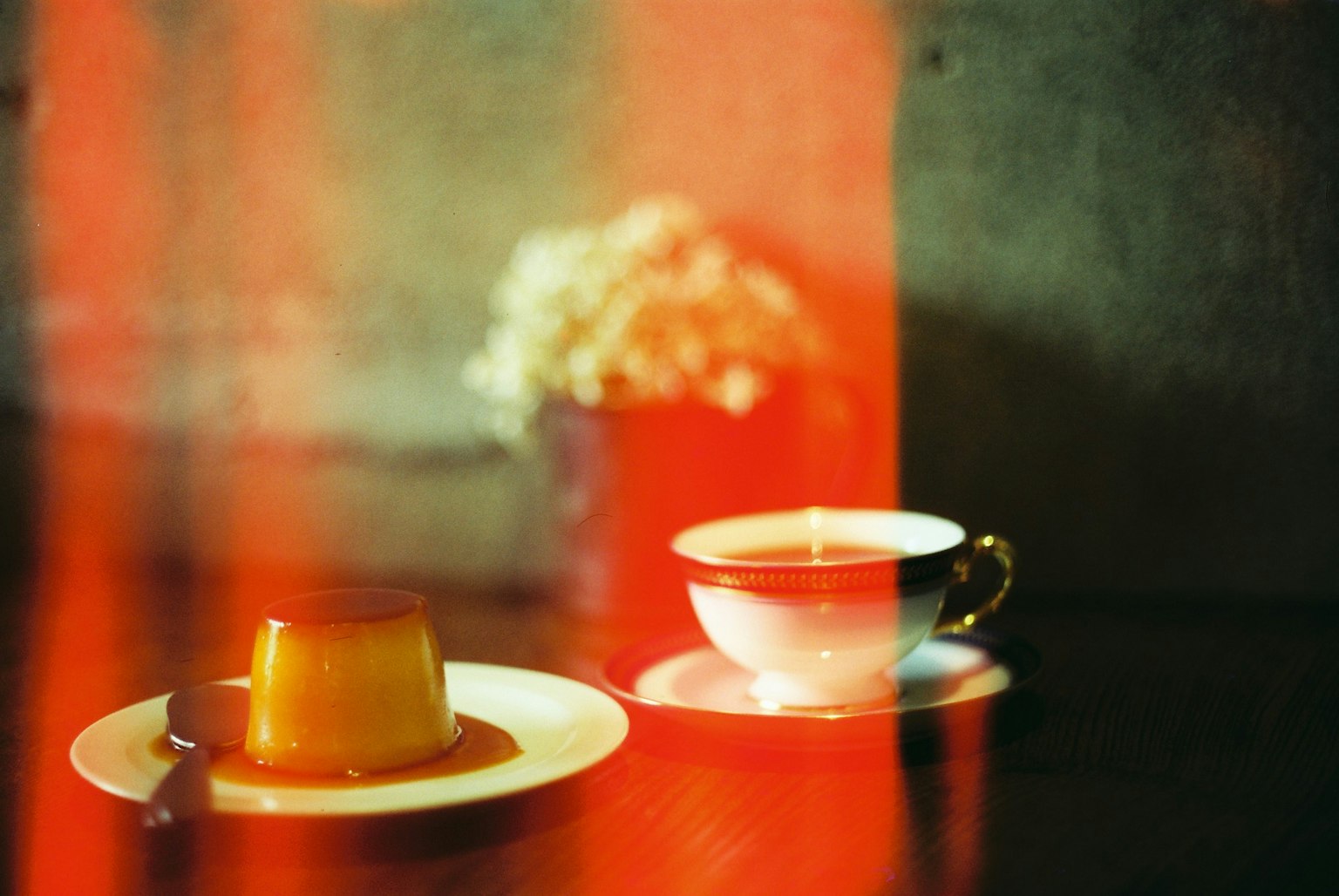 一張桌子上放著布丁和茶杯，背景色彩豐富