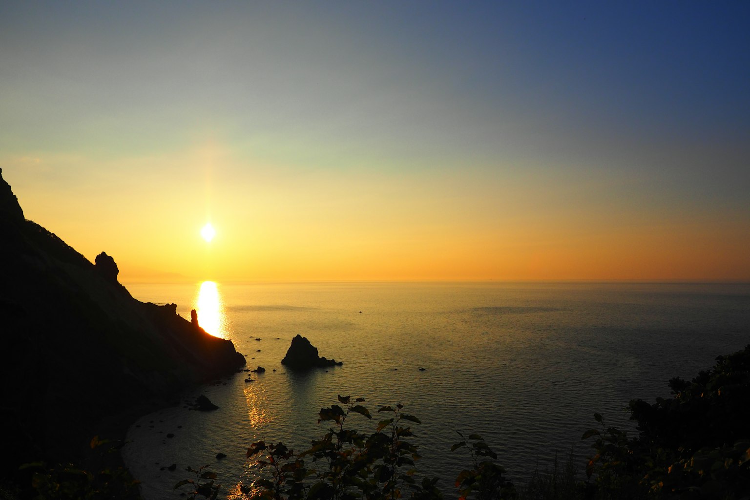 Schöner Sonnenuntergang über dem Meer mit Bergsilhouetten