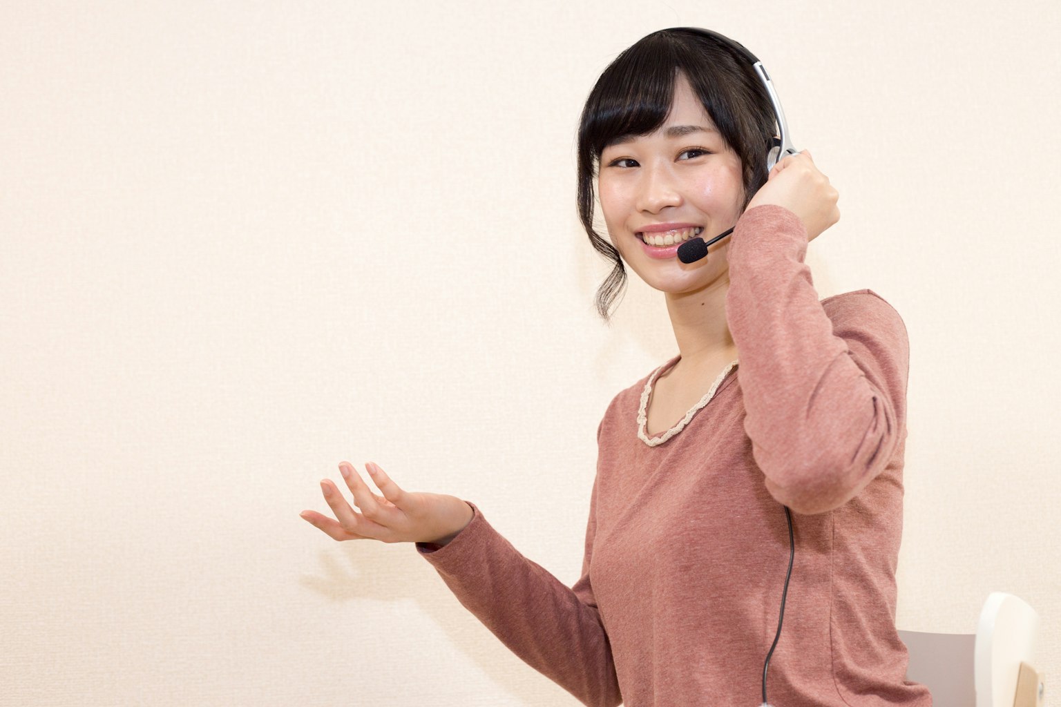 Une femme souriante portant un casque gesticulant de la main