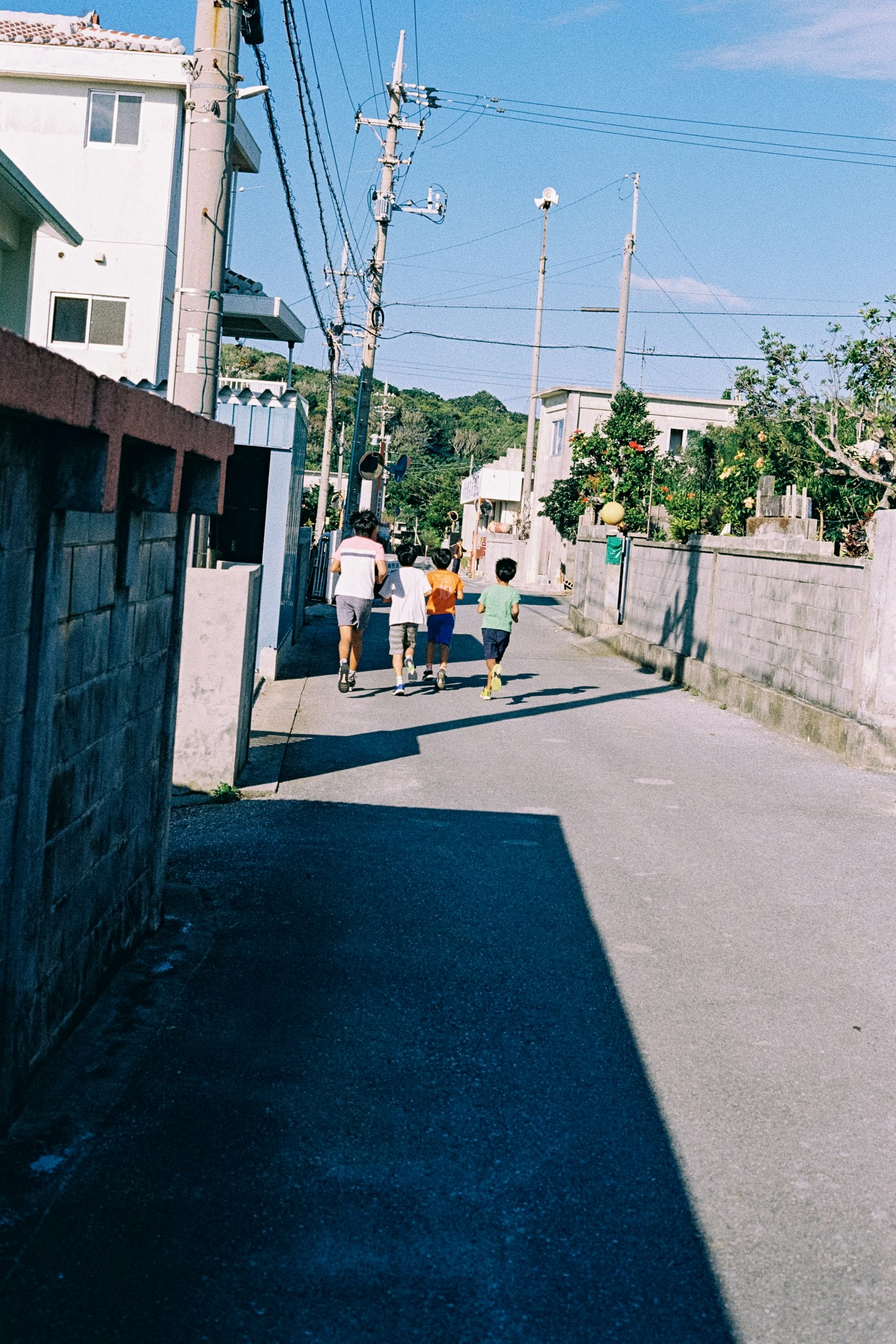 孩子们在狭窄的街道上奔跑，周围有房屋和电线杆