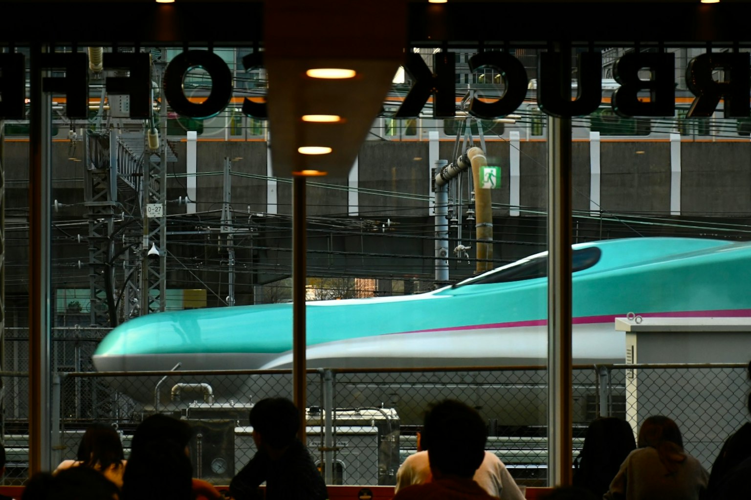 View of a Shinkansen train from a Starbucks window with people inside