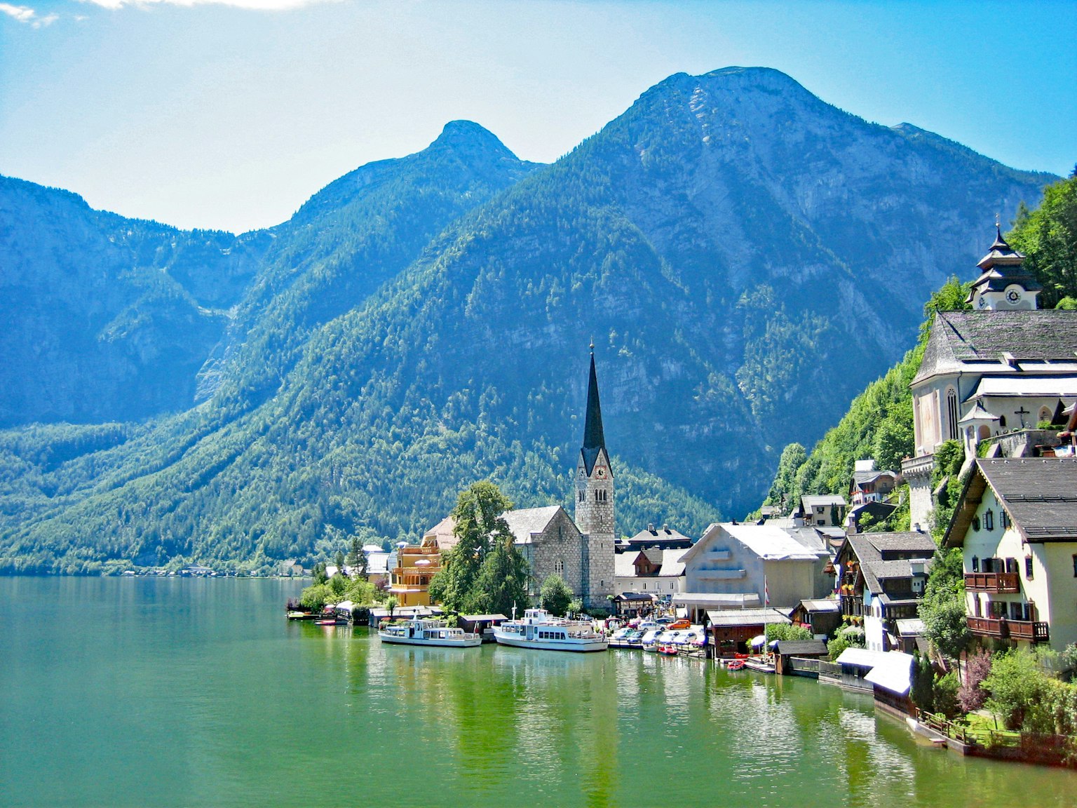 Malersicher Ausblick auf ein Dorf am See mit einem markanten Kirchturm, umgeben von Bergen