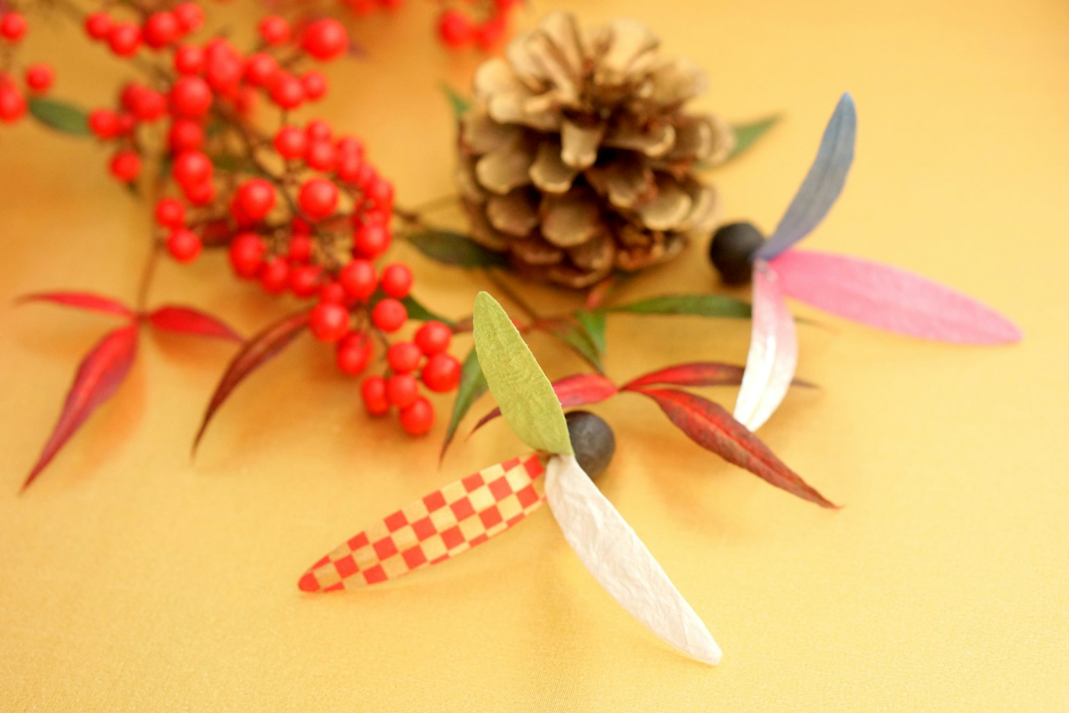 Feuilles colorées et éléments décoratifs placés sur un cône de pin et des baies rouges