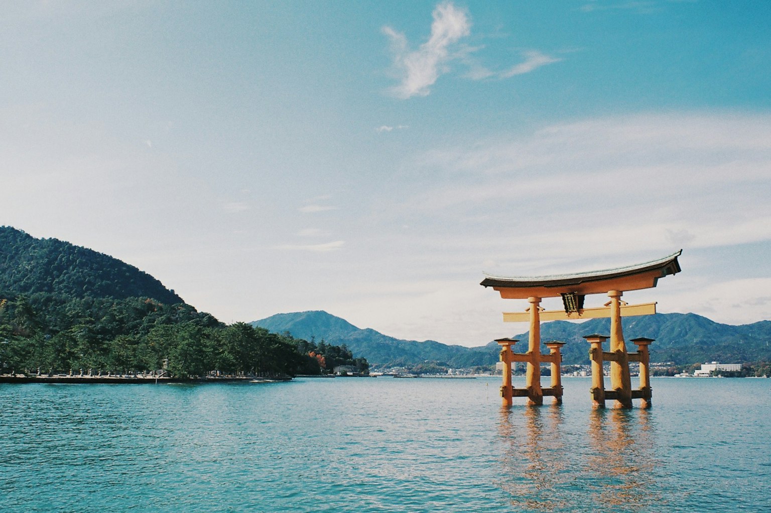 Gerbang torii mengapung dari Kuil Itsukushima dengan latar belakang pegunungan