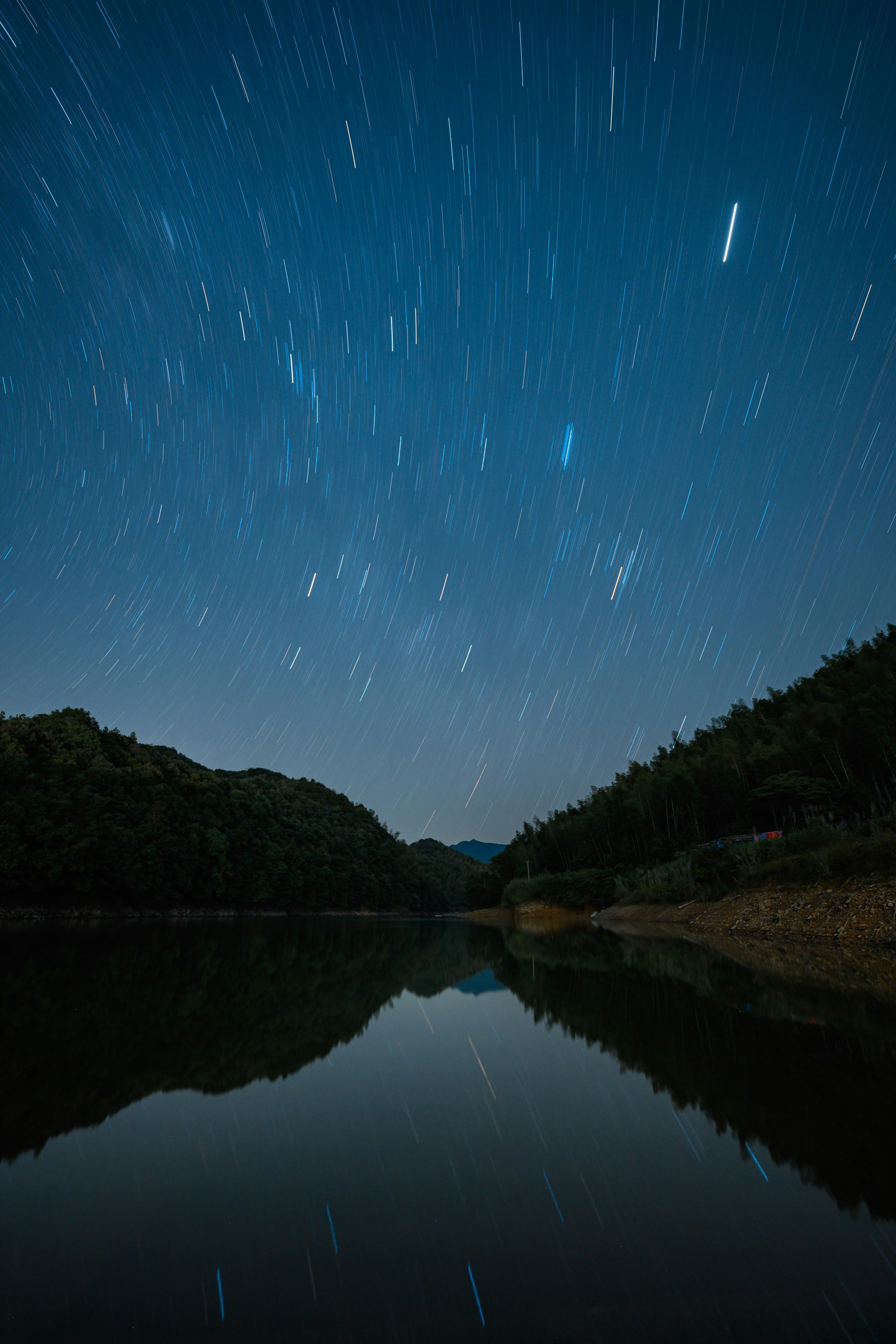 星空の下の静かな湖と山並みの夜景