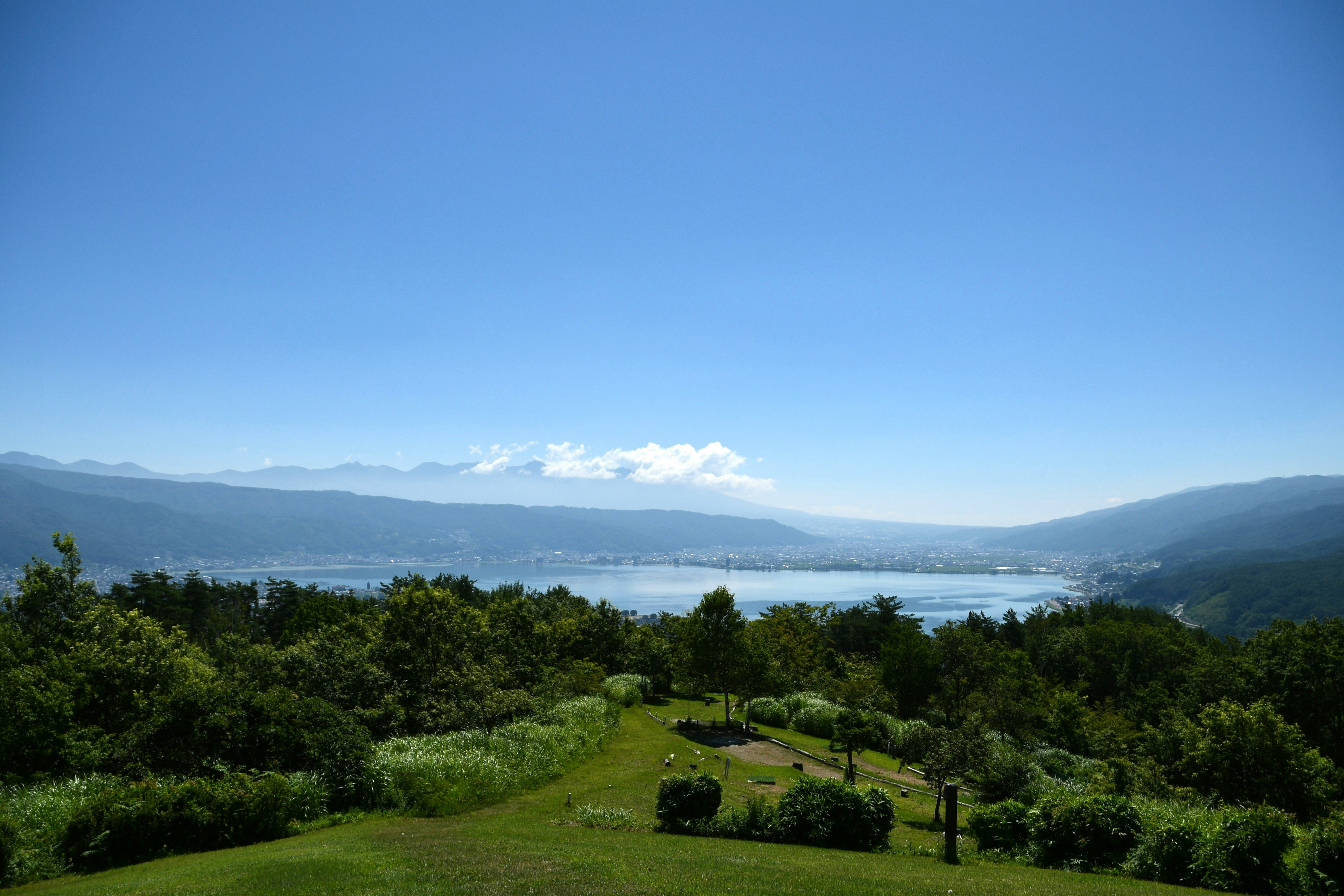 緑の丘と庭園から見渡す湖と山並みの絶景