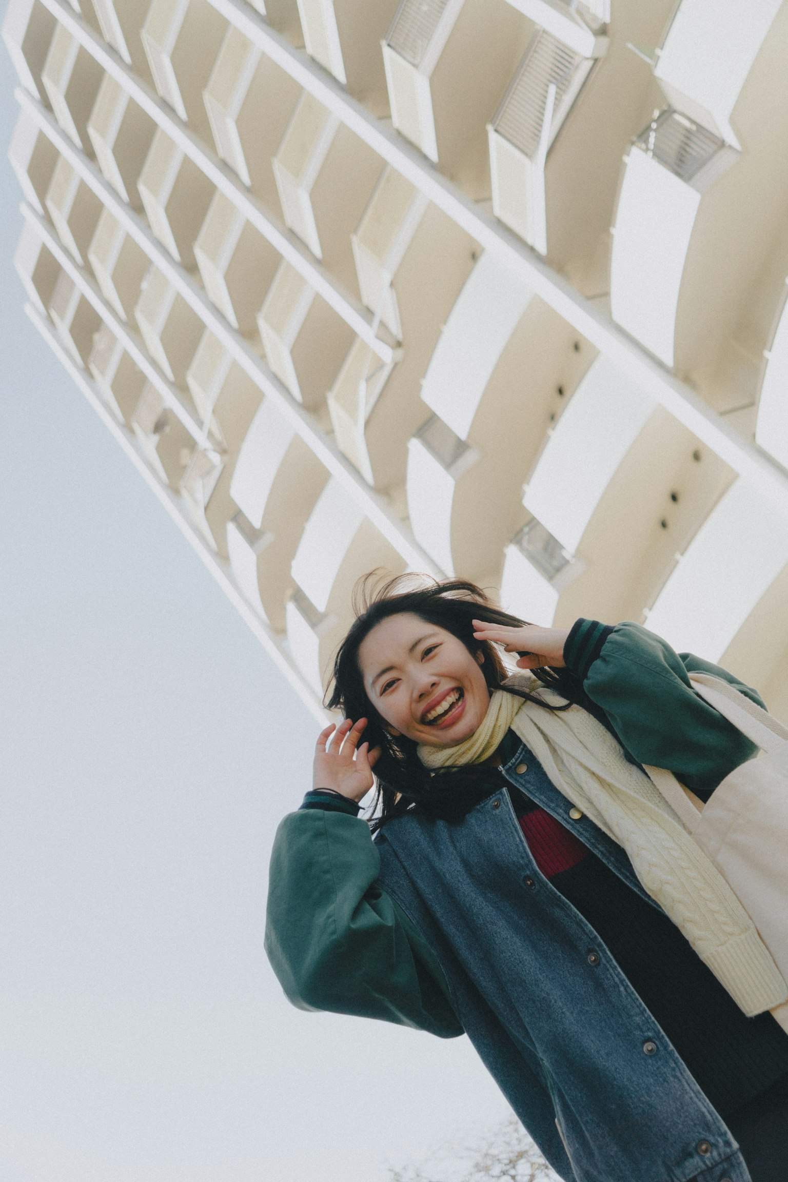 Donna sorridente che tocca i capelli davanti a un edificio bianco