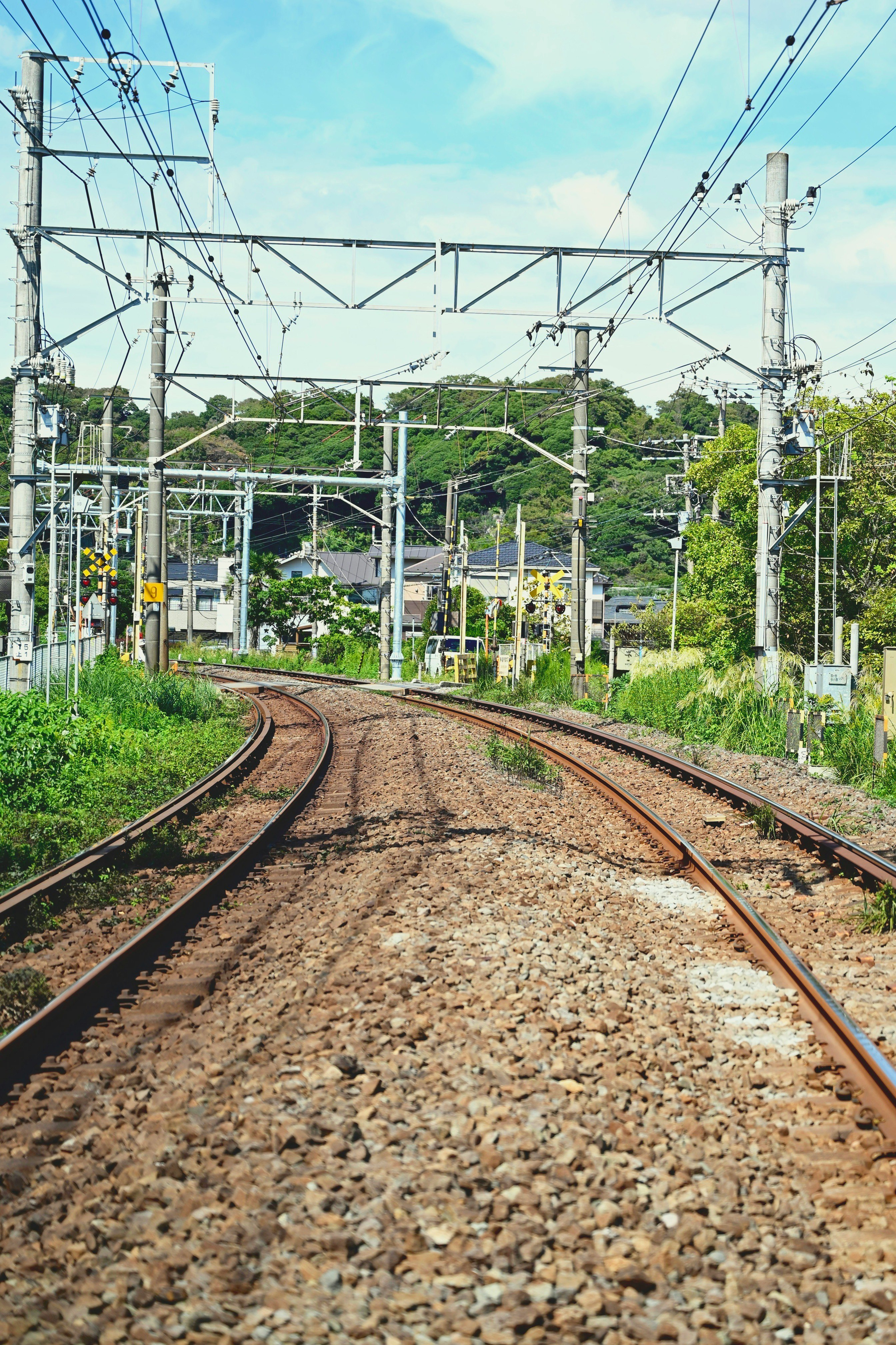 線路が伸びる電化区間の架線と鉄道設備のある風景