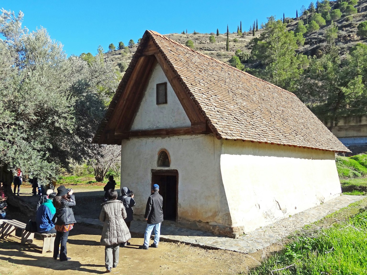 Gruppo di persone che si avvicina a una vecchia casa con un tetto triangolare in legno