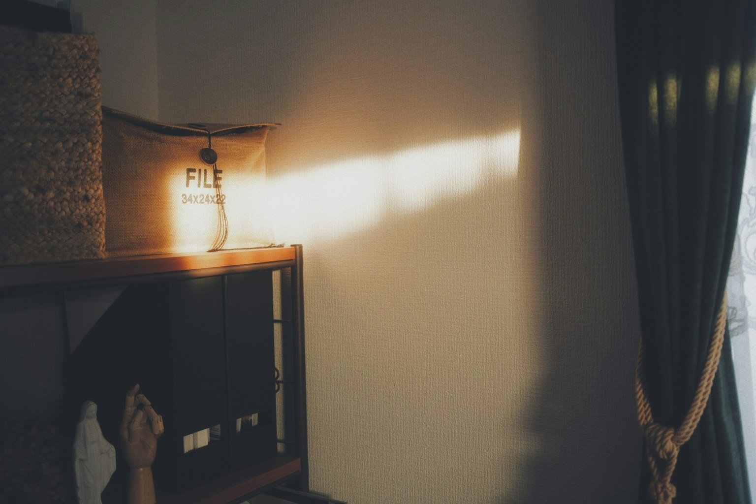 Una esquina de una habitación simple con luz reflejándose en la pared