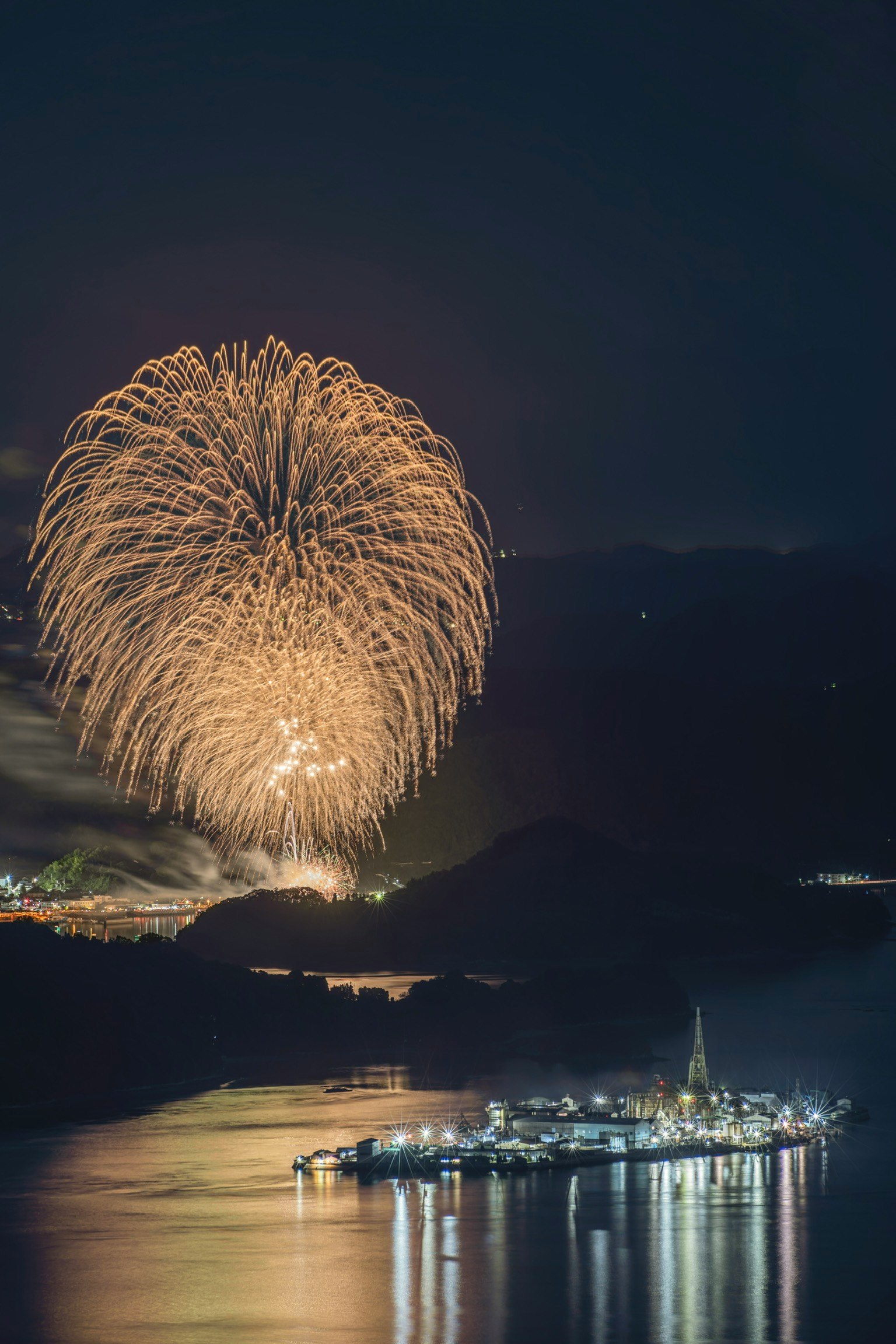 Feuerwerke erhellen den Nachthimmel und spiegeln sich im Wasser mit einer malerischen Aussicht