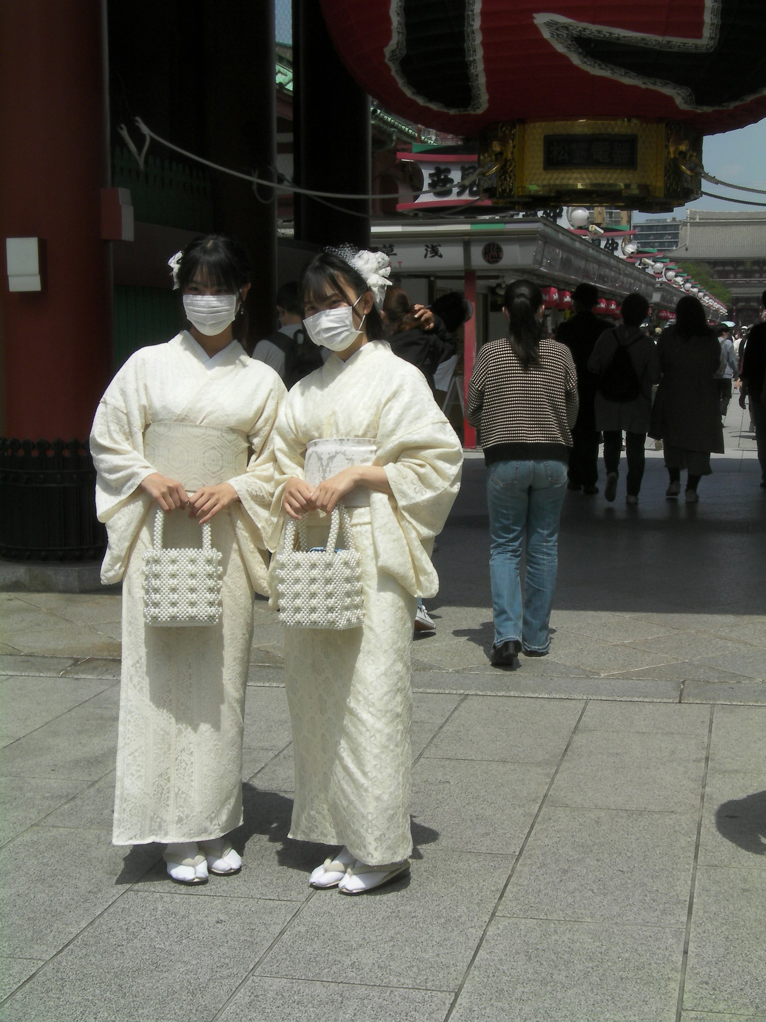 Dos mujeres en kimonos blancos usando mascarillas de pie juntas
