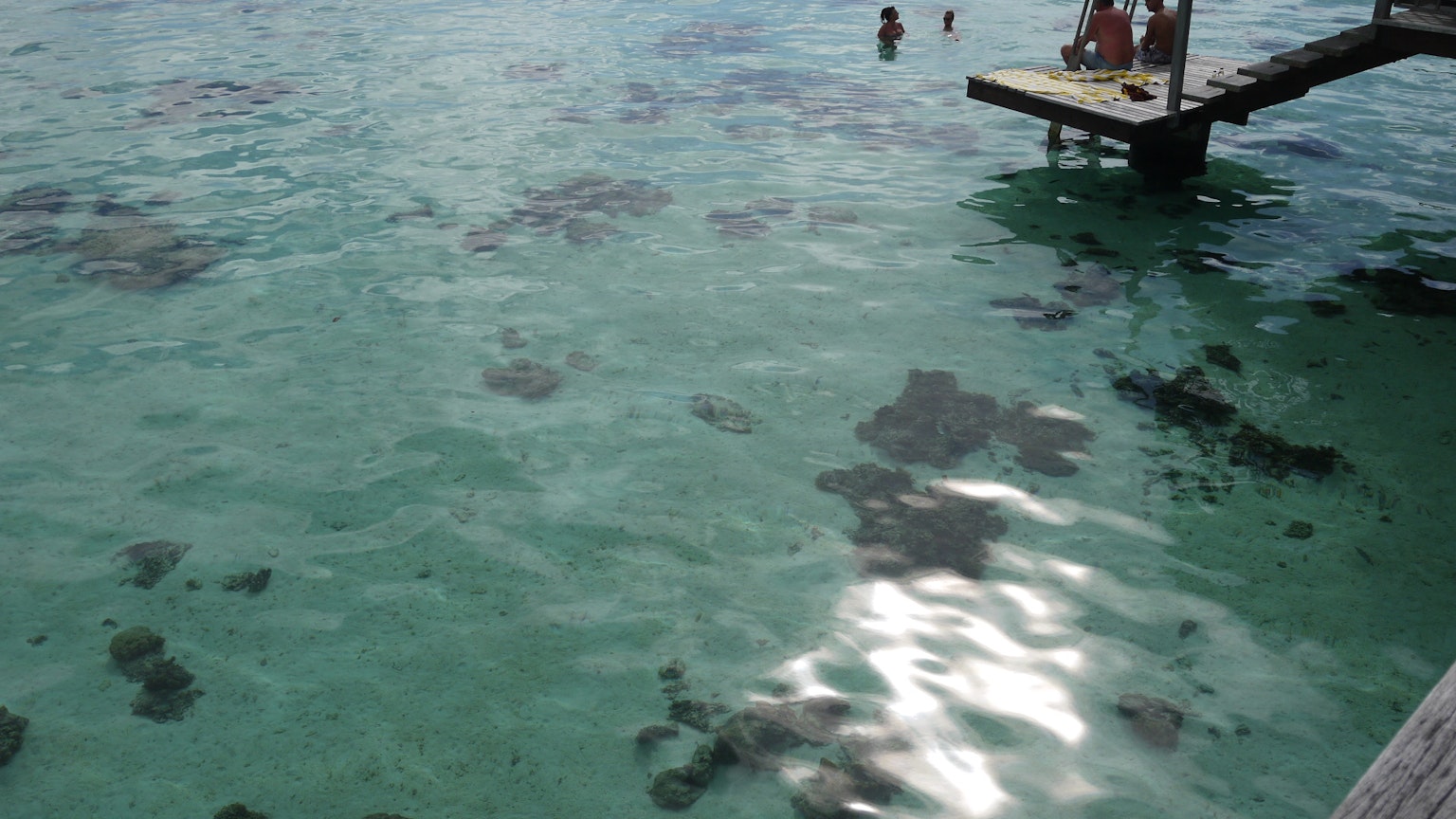 Eau turquoise claire avec des personnes et un quai
