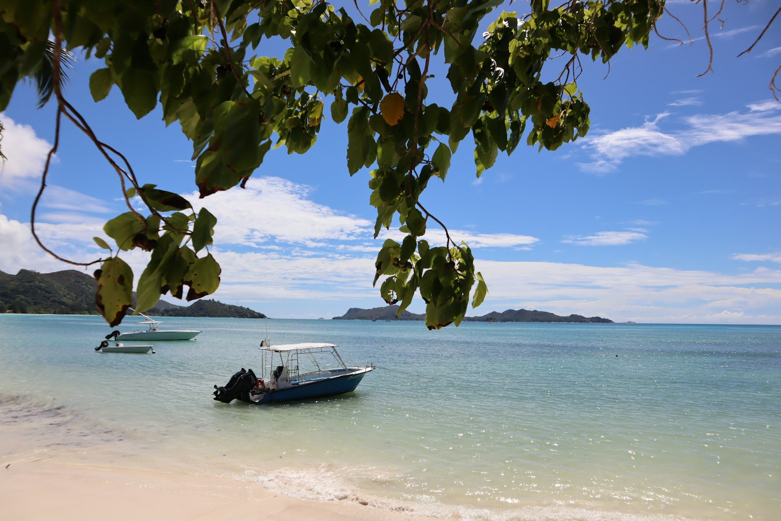 Pemandangan indah perahu di air biru dengan pantai berpasir putih dan langit cerah