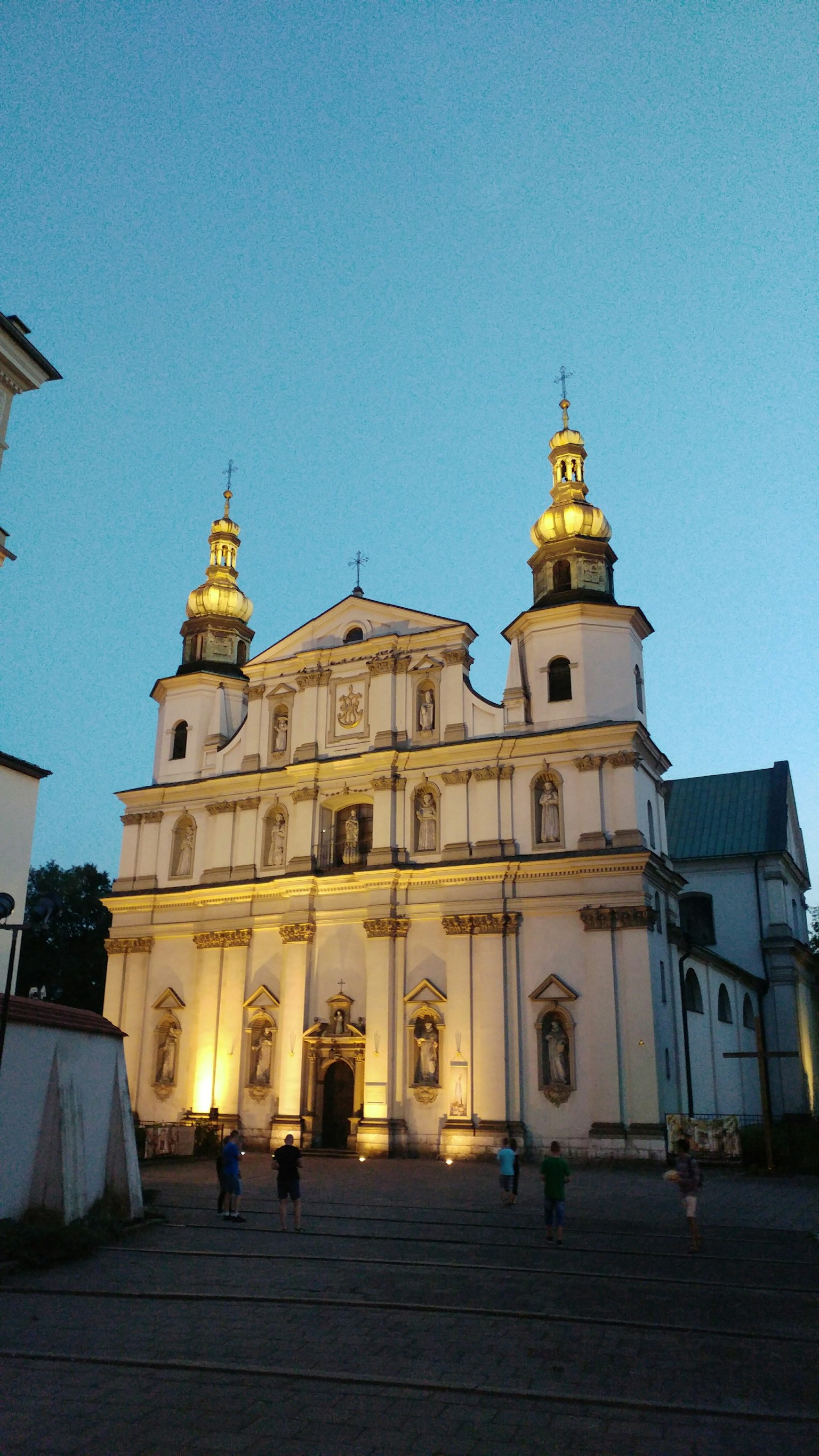 Hermosa fachada de iglesia bajo un cielo crepuscular con cúpulas doradas y luces