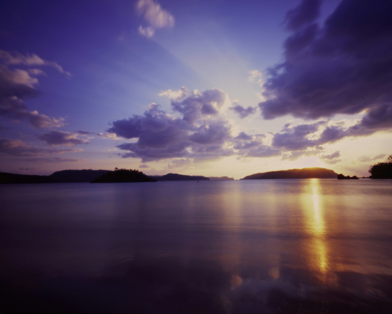 Coucher de soleil serein sur l'océan avec des nuages et des îles