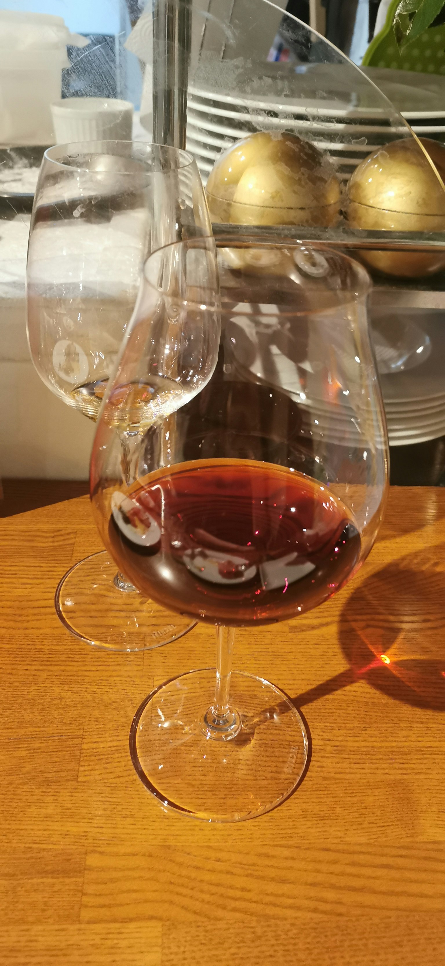A glass of red wine on a wooden table with reflections and bubbles