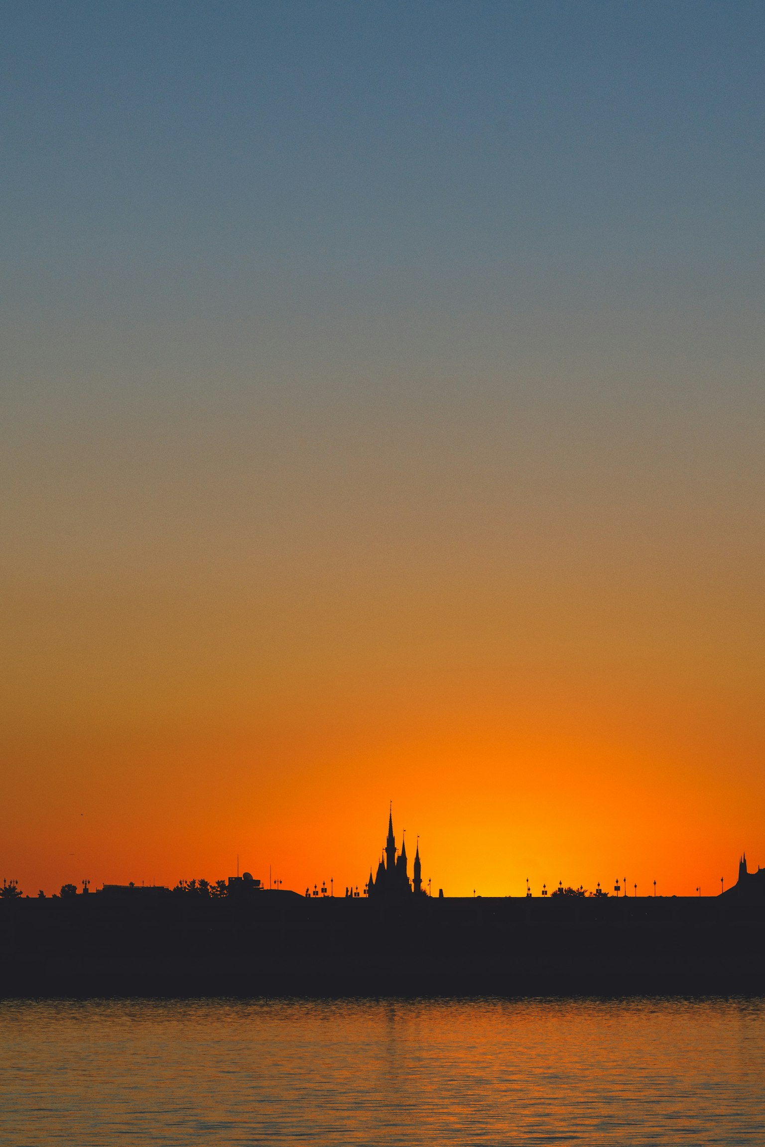 Schöne Silhouette einer Skyline vor einem orangefarbenen Sonnenuntergang, der sich im Wasser spiegelt