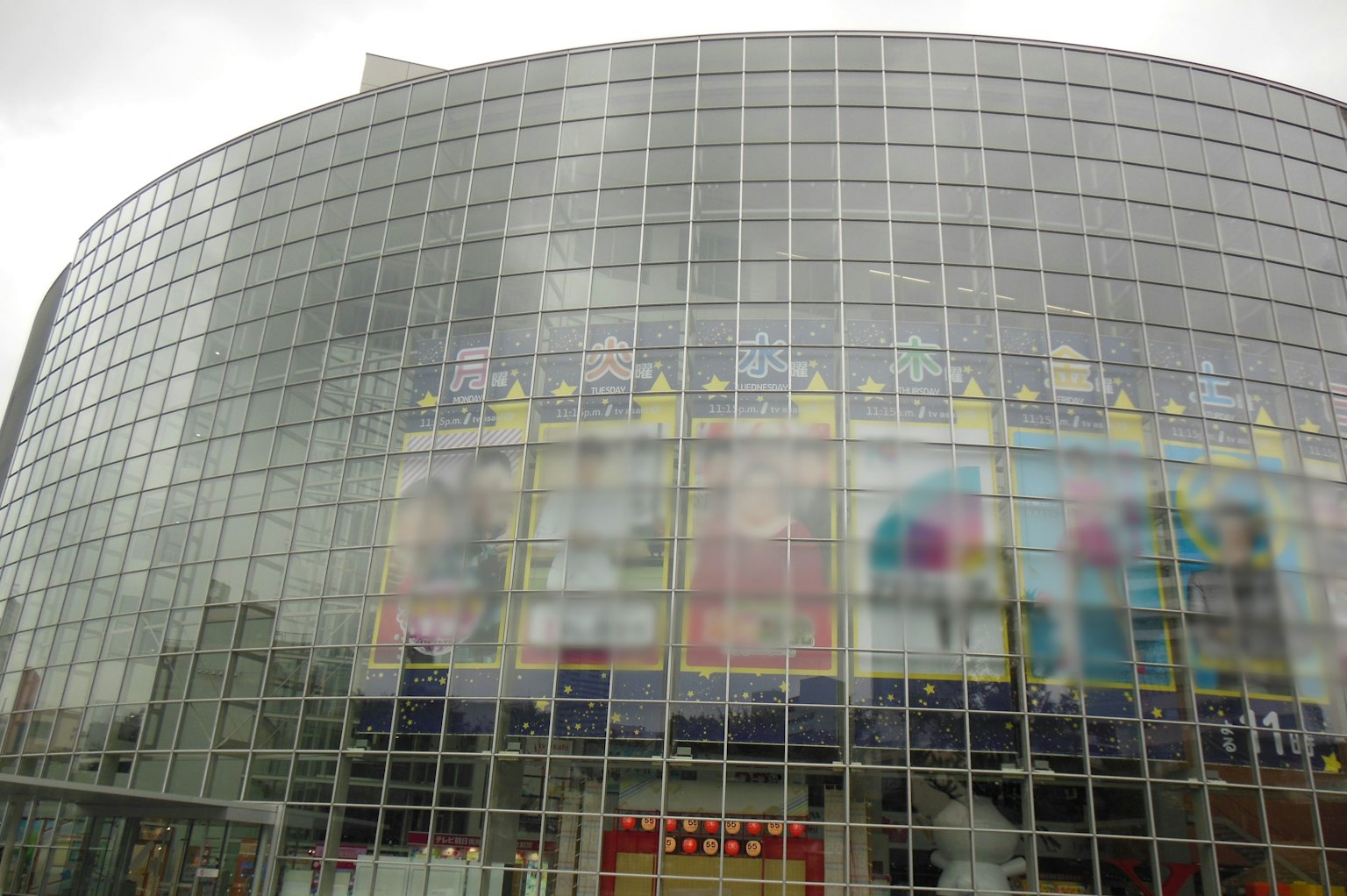 现代建筑，拥有大型玻璃外立面，展示各种广告
