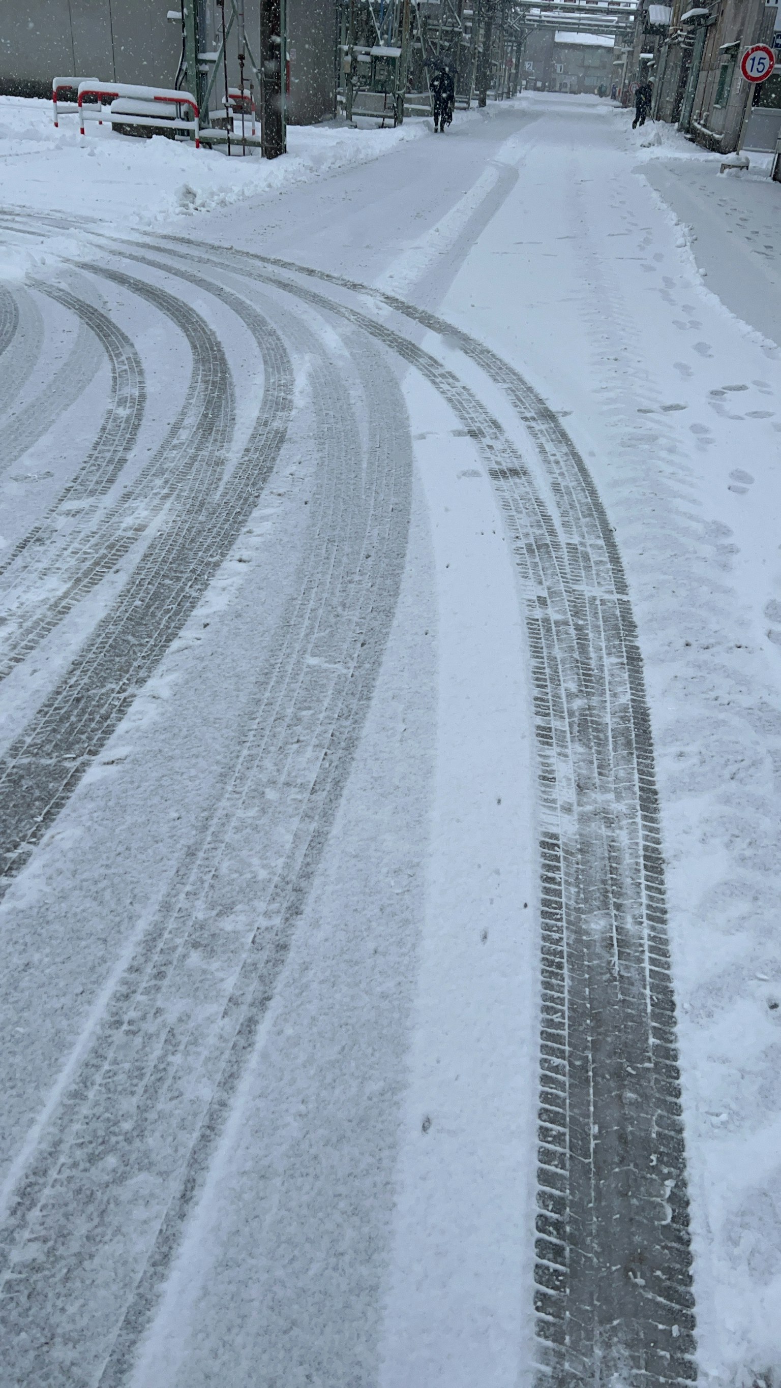 Kurvenreiche, verschneite Straße mit sichtbaren Reifenspuren