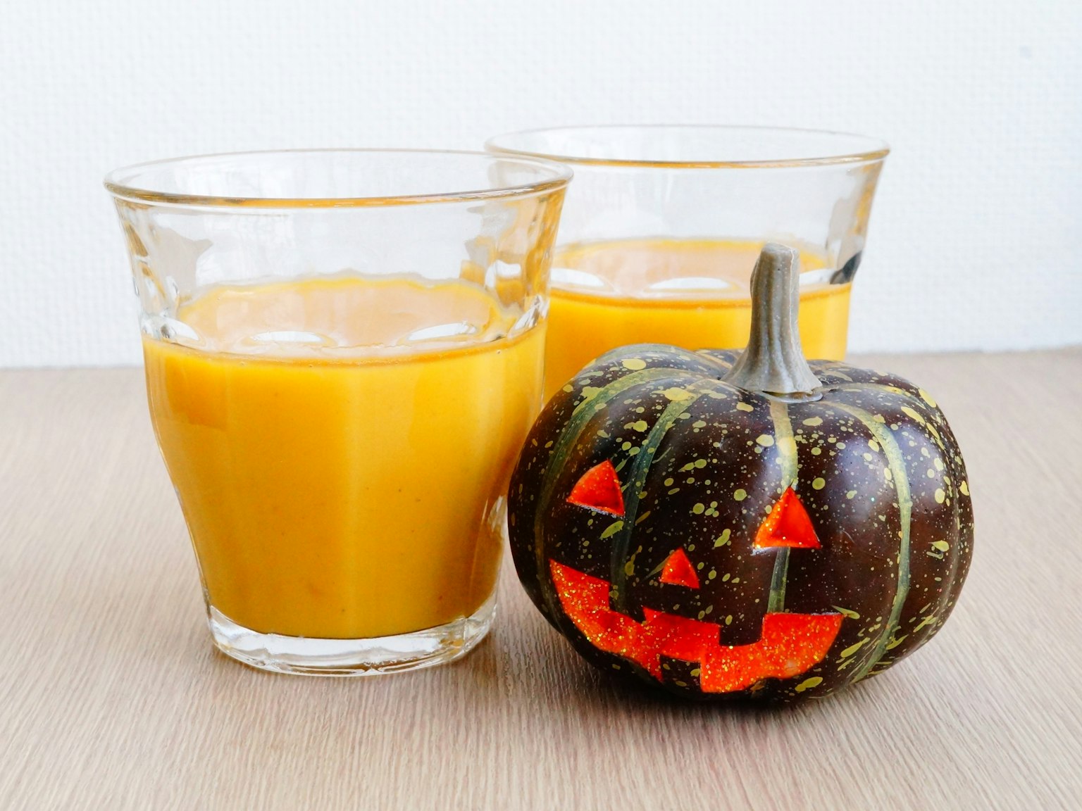 Dos vasos de jugo de naranja junto a una calabaza de Halloween