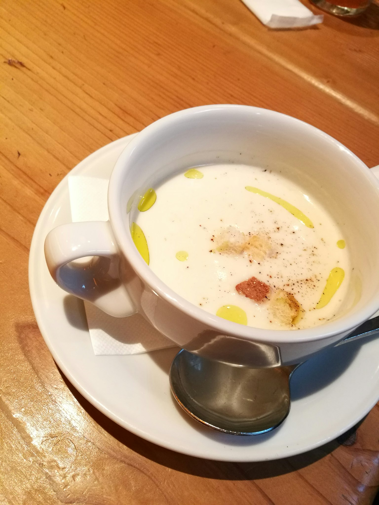Soupe crémeuse dans une tasse blanche garnie d'huile d'olive et de croûtons