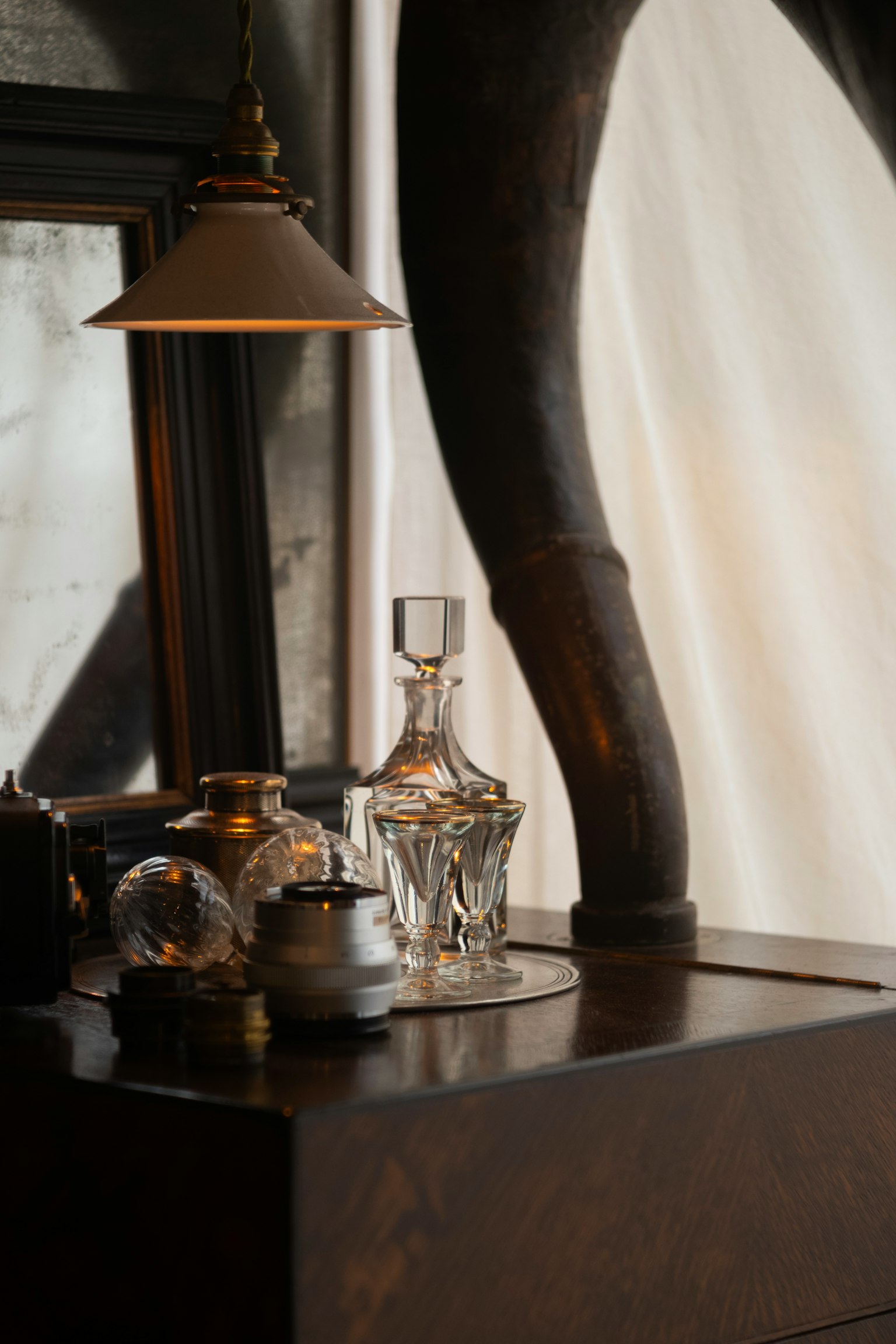 Eleganter Dekanter und silberne Teekanne auf einem Holztisch mit einer Lampe