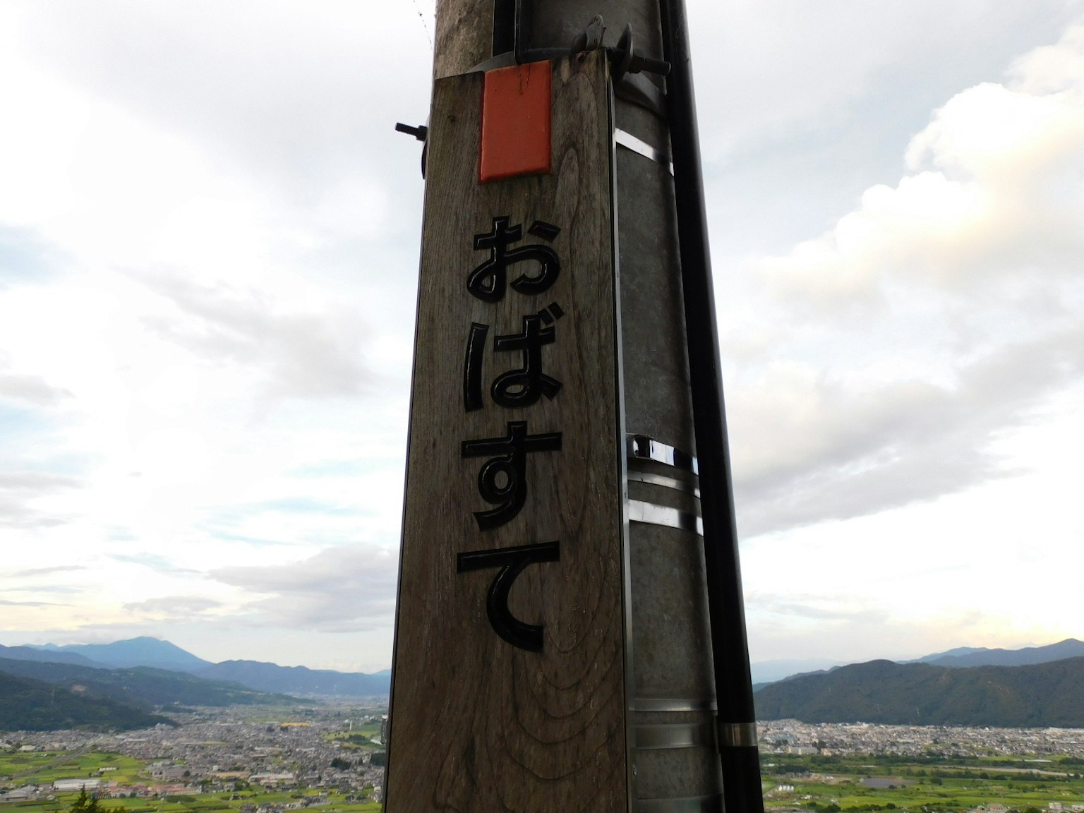 木柱上寫著'おばすて'的字樣和風景背景