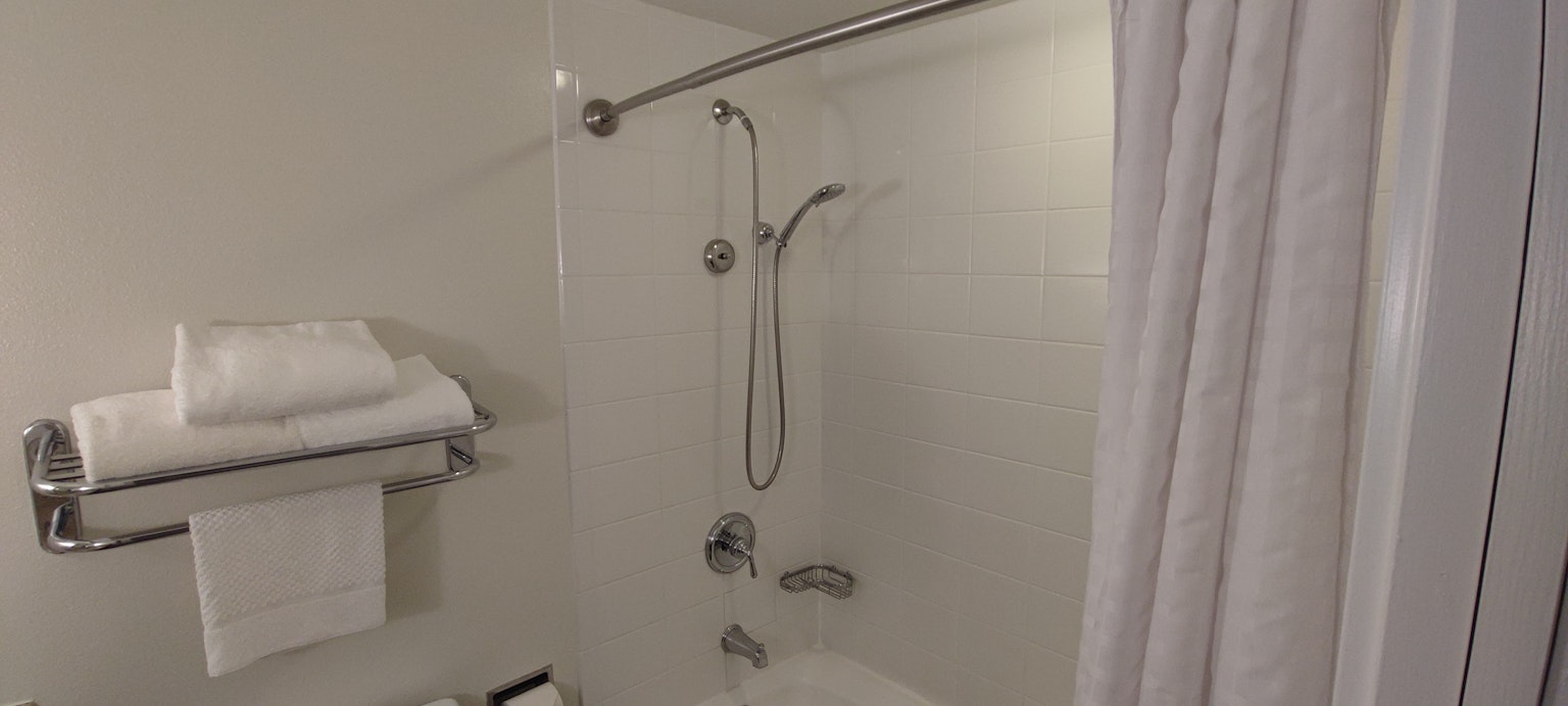 Area doccia pulita in un bagno con asciugamani su uno scaffale
