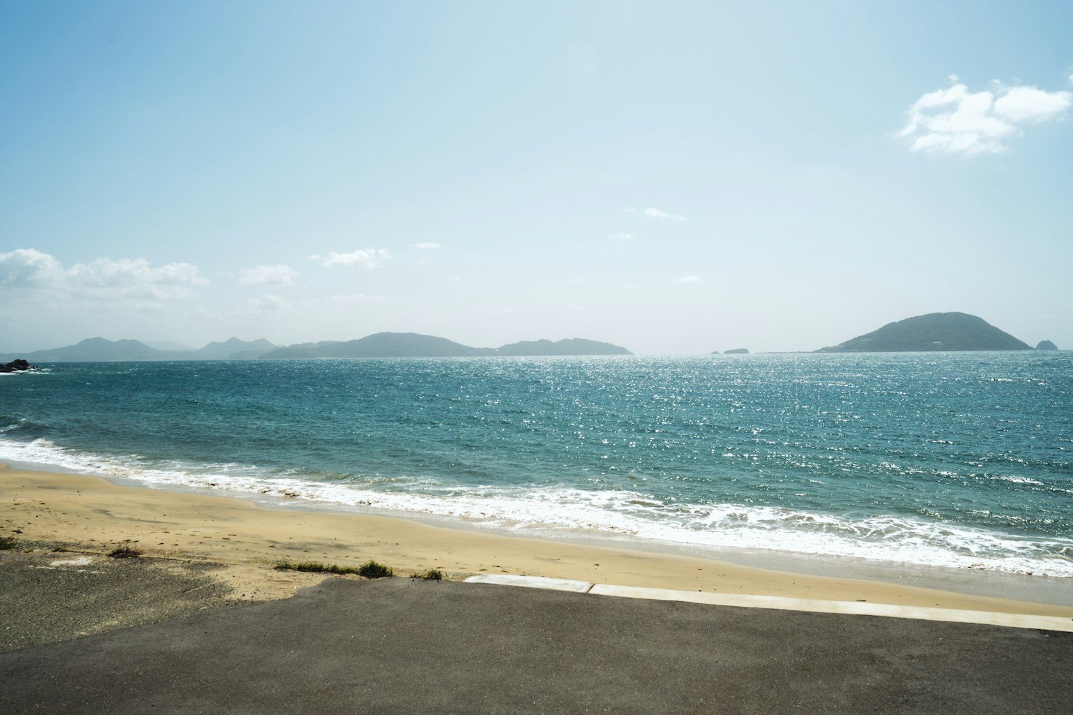 Pemandangan indah laut biru dan pantai berpasir dengan pulau-pulau di kejauhan