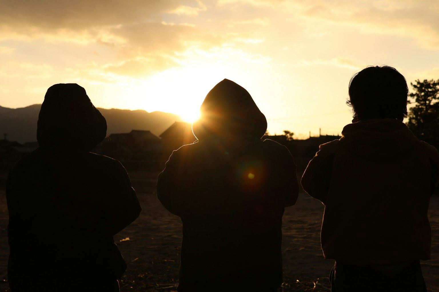 Silhouette von drei Personen vor einem Sonnenuntergang