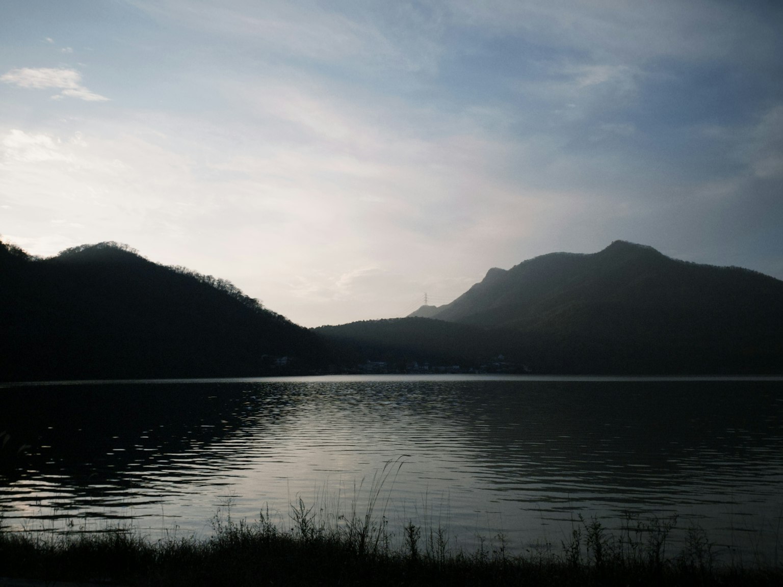 Vista serena junto al lago con montañas al anochecer superficie de agua tranquila
