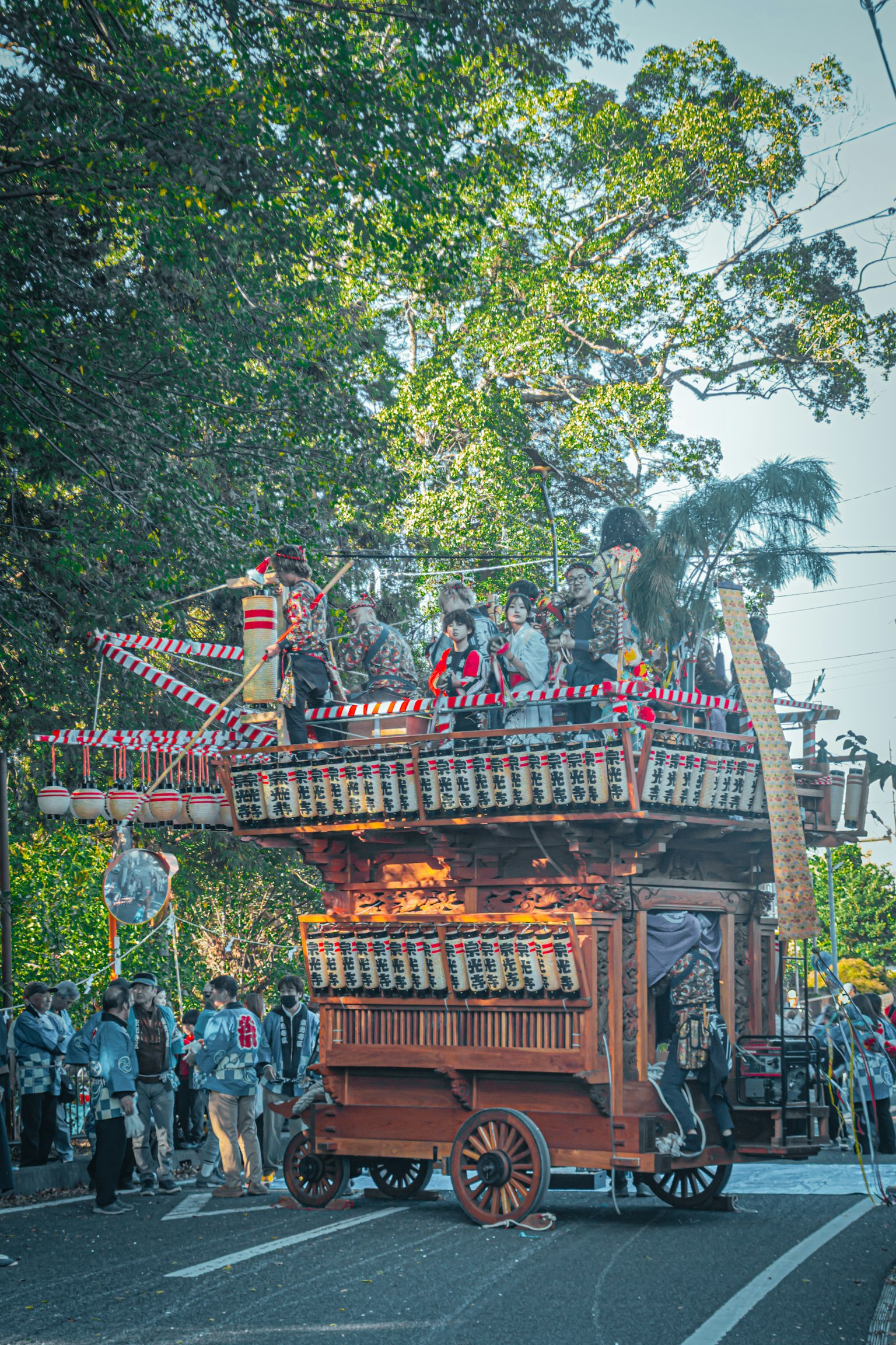 祭りの山車が通りを進む様子 人々が周りに集まっている