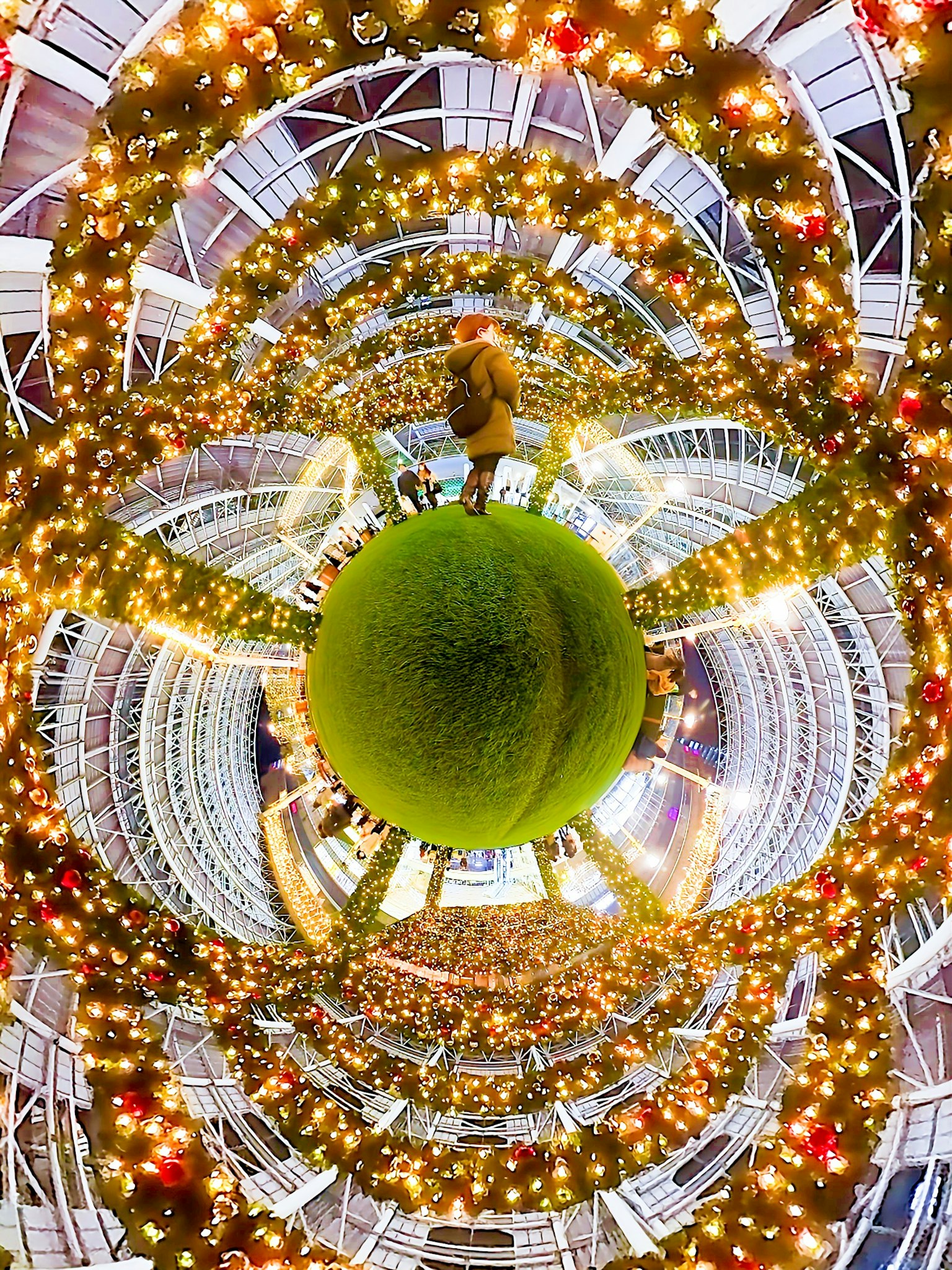 Persona de pie sobre una esfera verde rodeada de decoraciones de luz circulares