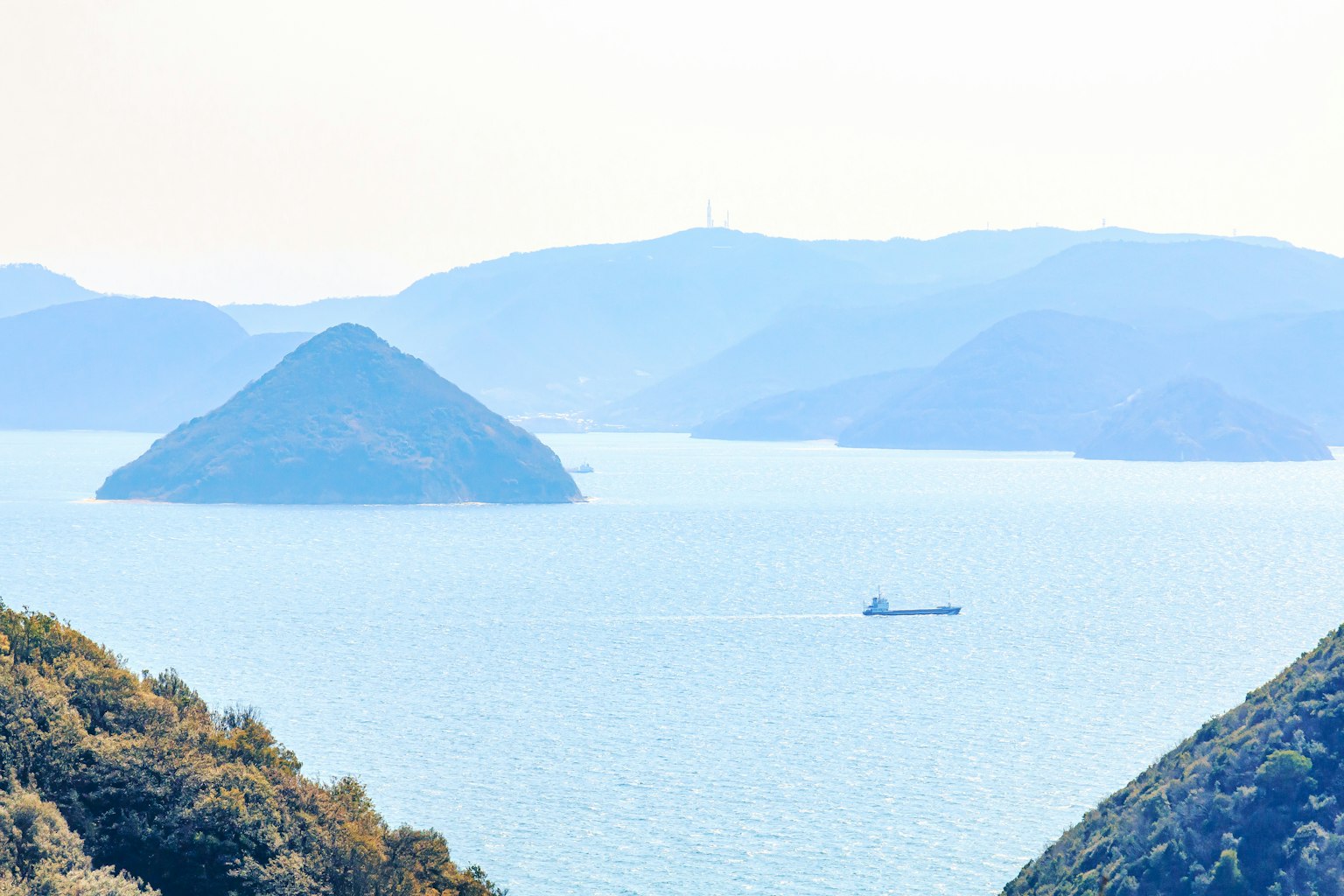 Un paesaggio sereno con mare blu e montagne in silhouette con una piccola barca che galleggia