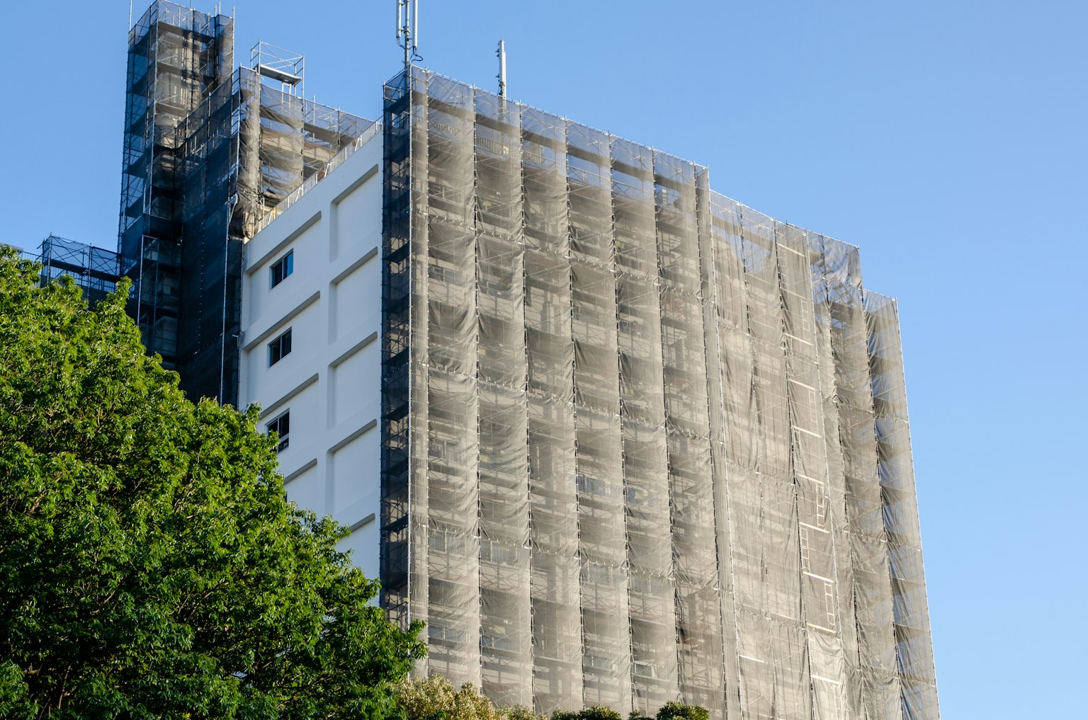 Edificio de gran altura en renovación con andamios y cielo azul claro