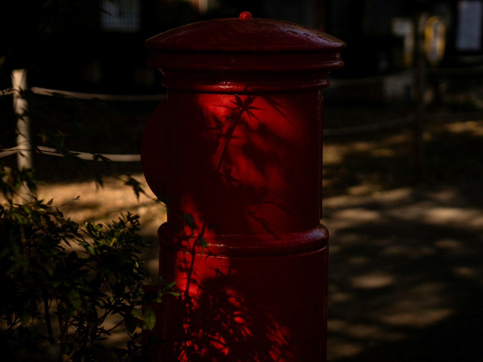 赤い郵便ポストに影が映る風景