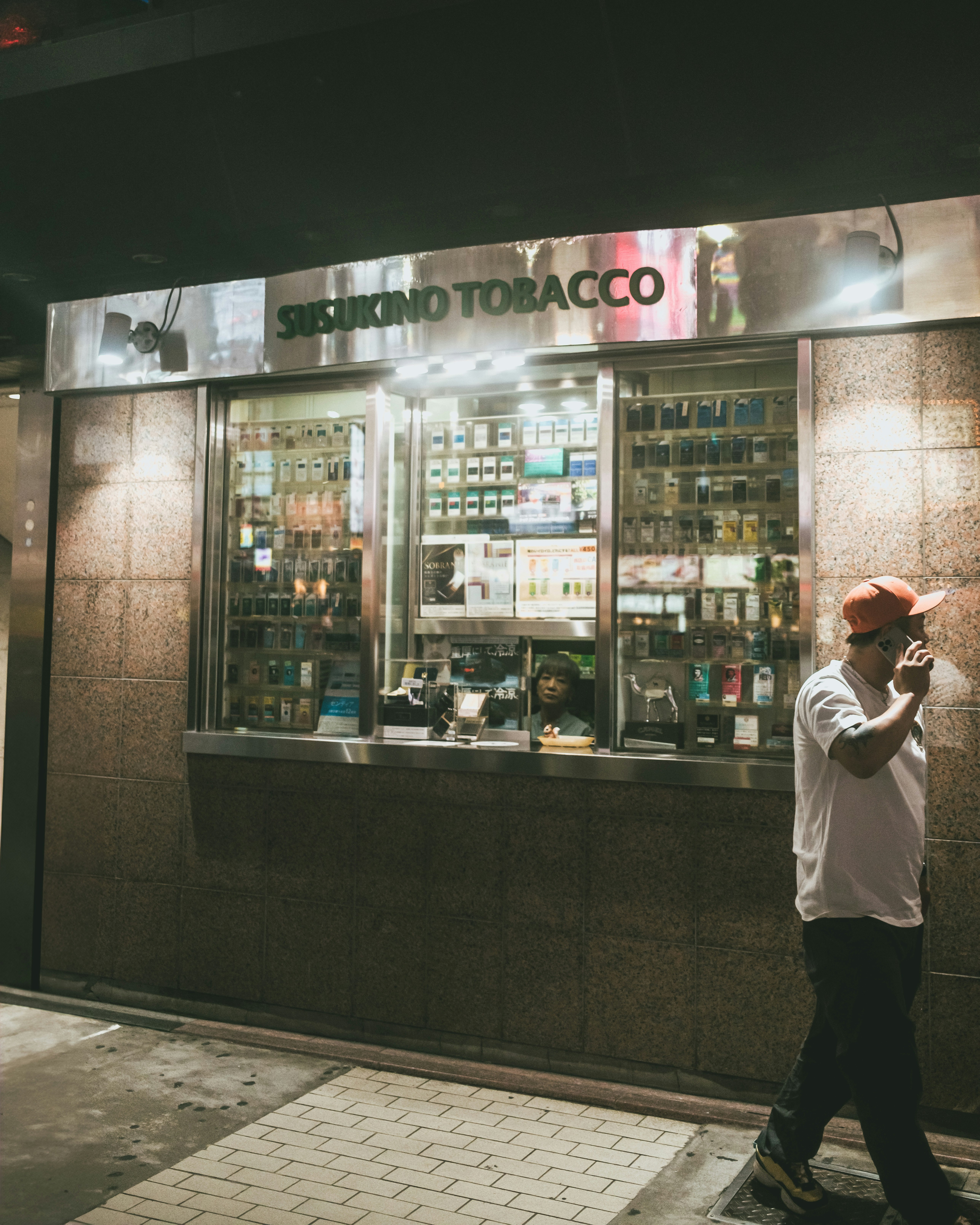 street storefront with a display case and a person on the phone