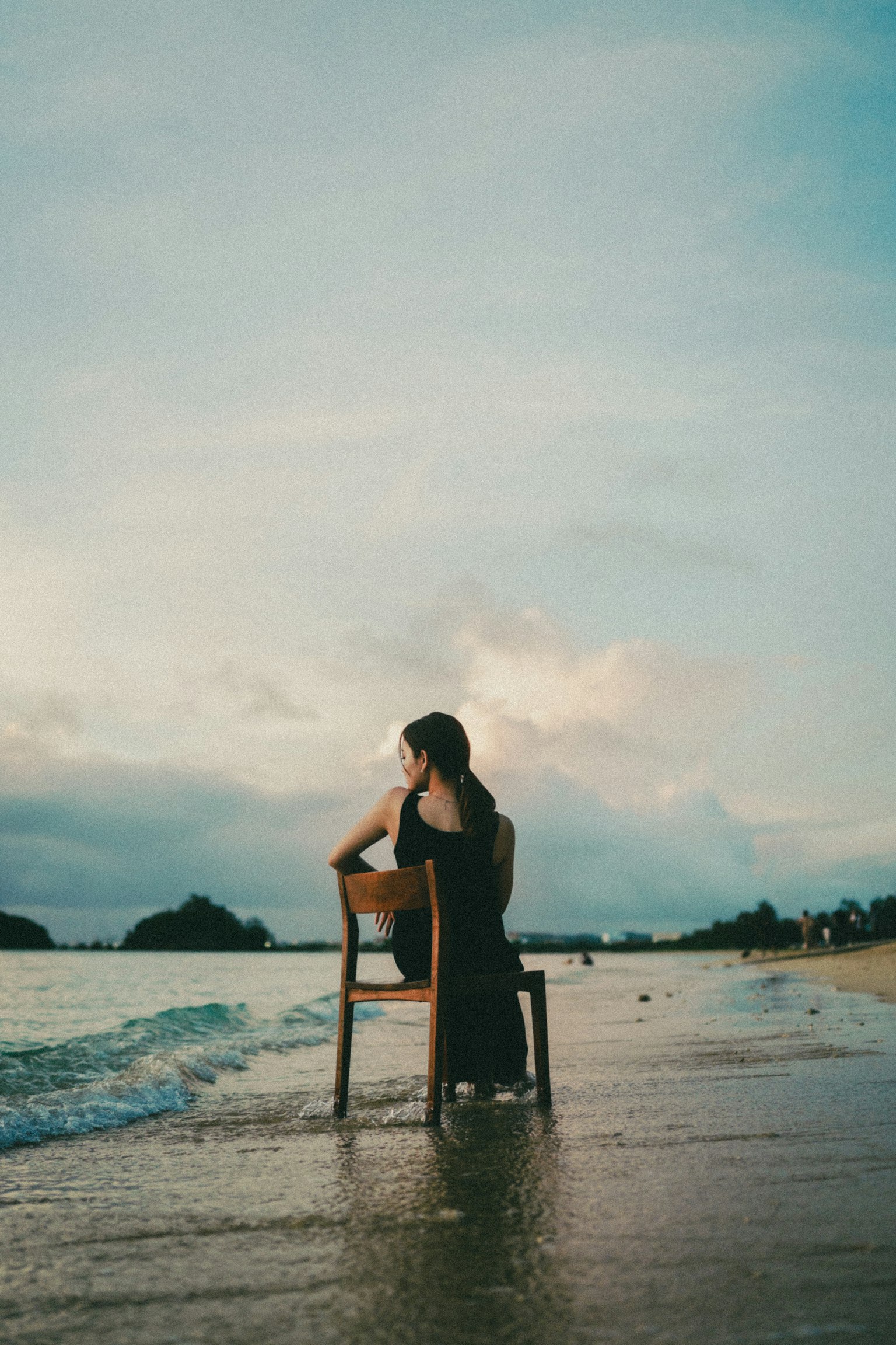 Une femme assise sur une chaise à la plage avec l'océan et le ciel en arrière-plan