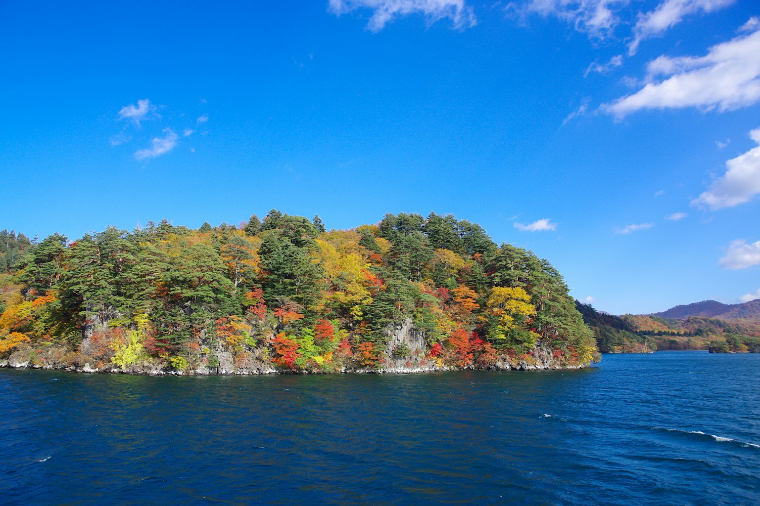 青空と色づいた木々に囲まれた湖の島