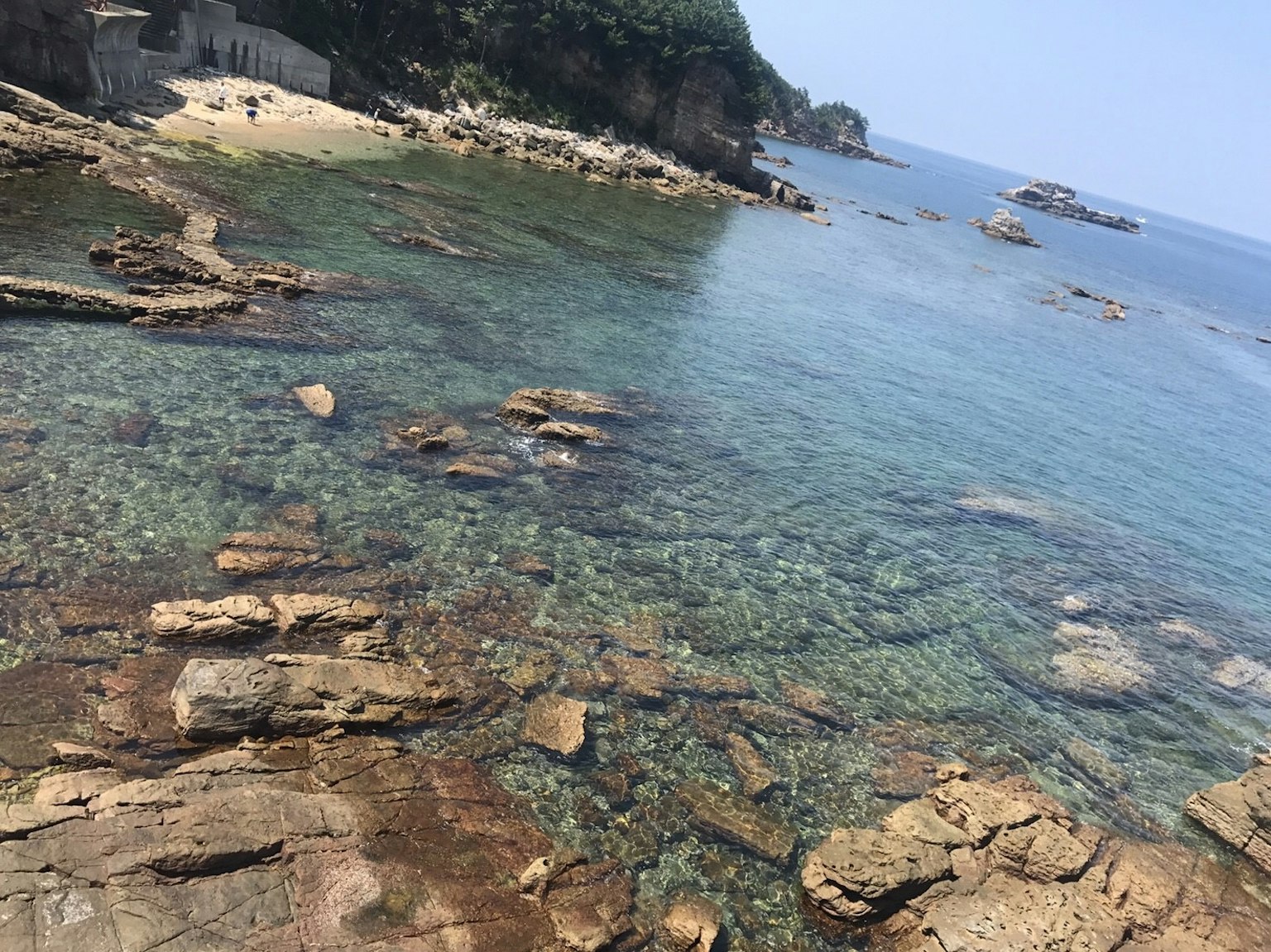 Rocky shoreline with clear water and distant islands