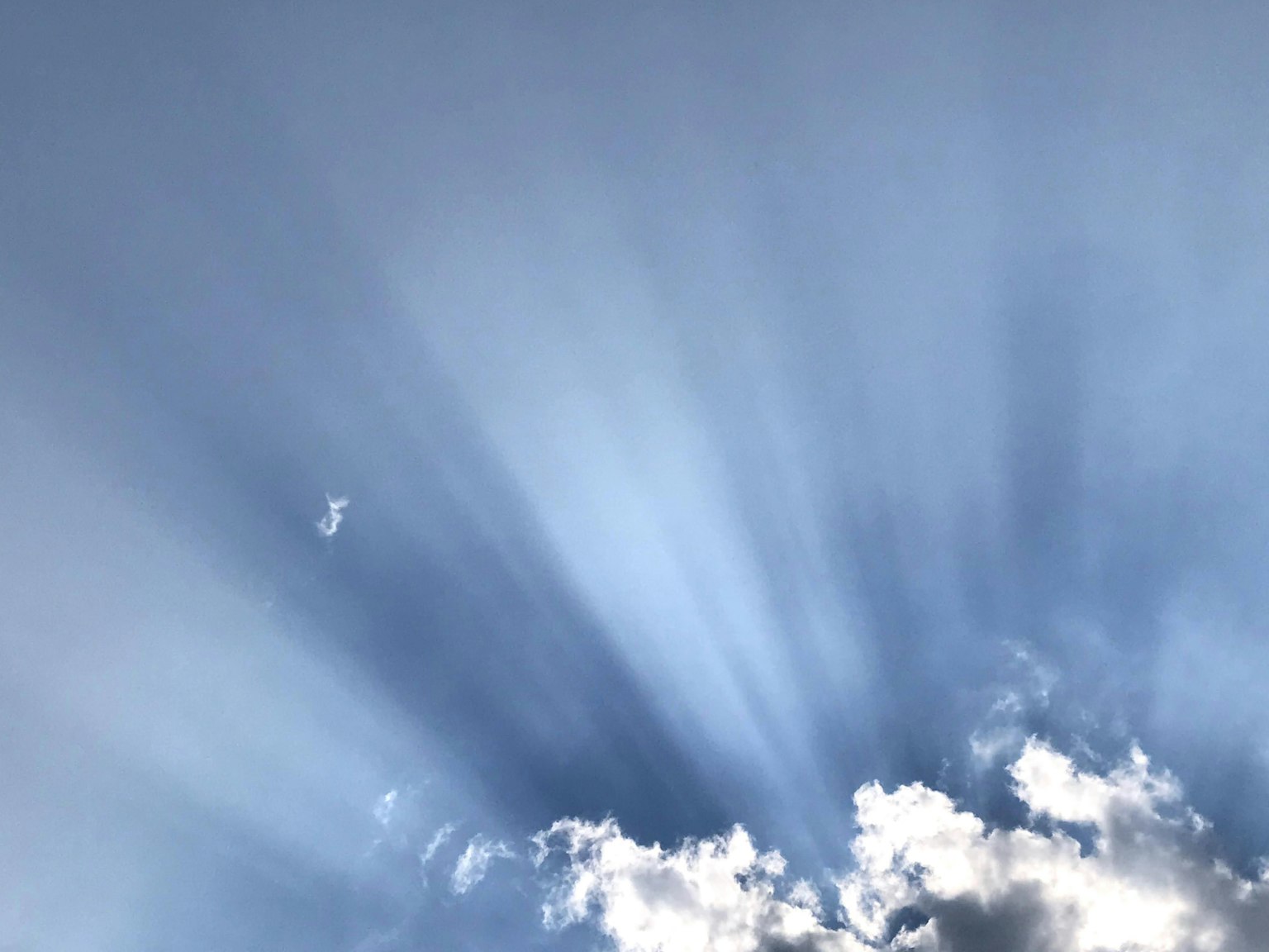 Light rays streaming through clouds in a blue sky