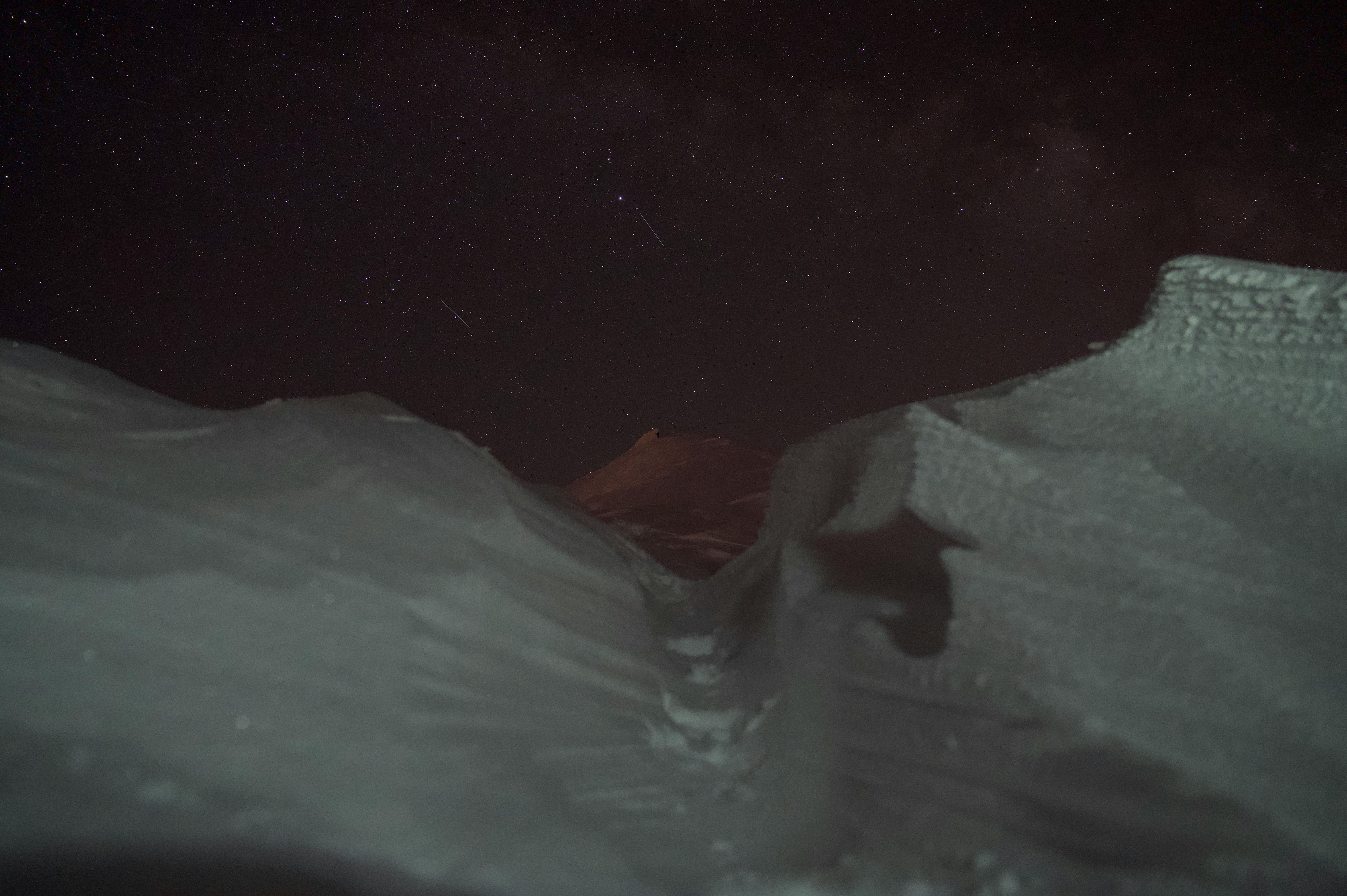 Silhouette of a small boat floating on dark water under a night sky
