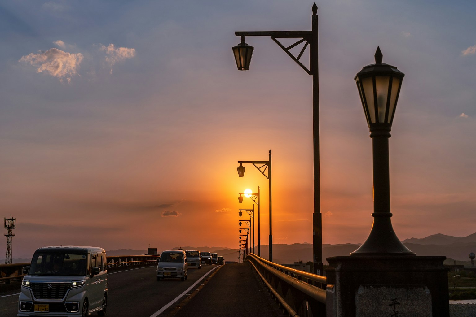 Malersicher Blick auf eine Brücke bei Sonnenuntergang mit Autos und Laternen